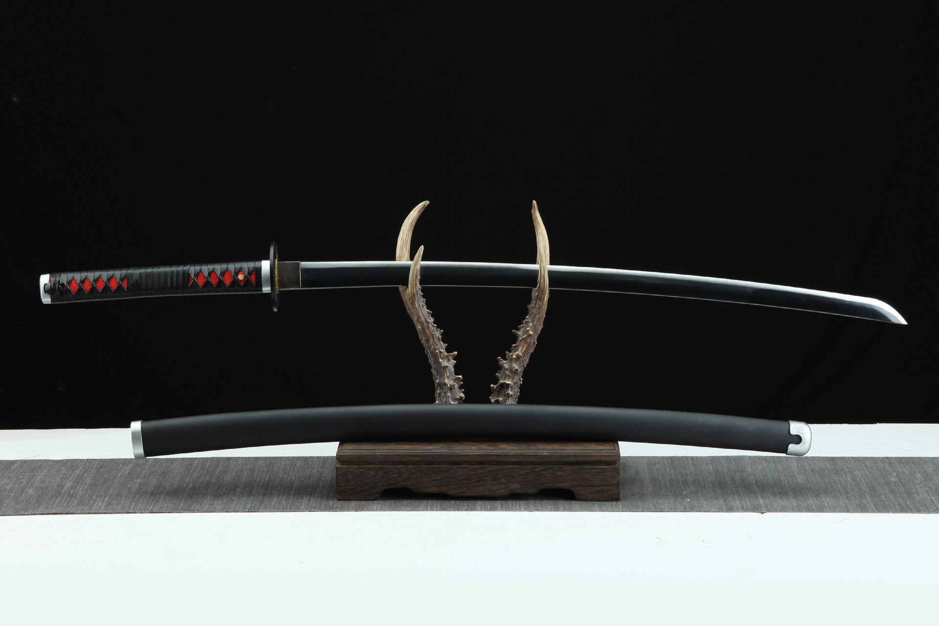 Tanjiro Kamado's obsidian black Nichirin sword and scabbard displayed on a stand, showcasing exquisite craftsmanship for Demon Slayer fans.