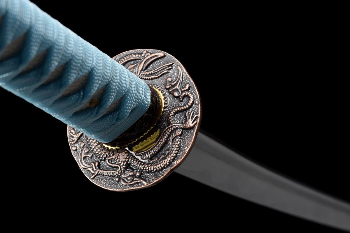 Close view of the dragon-motif alloy guard and light blue handle wrap