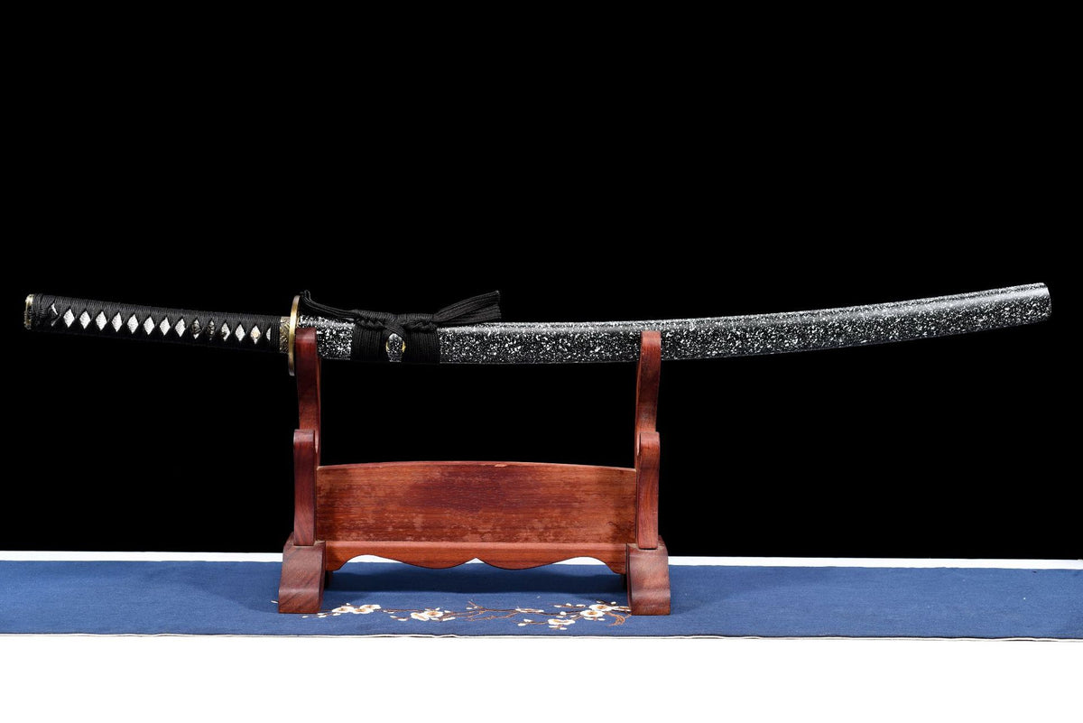 Inkstorm Samurai Katana sheathed on a stand, showing the black-and-white splatter saya