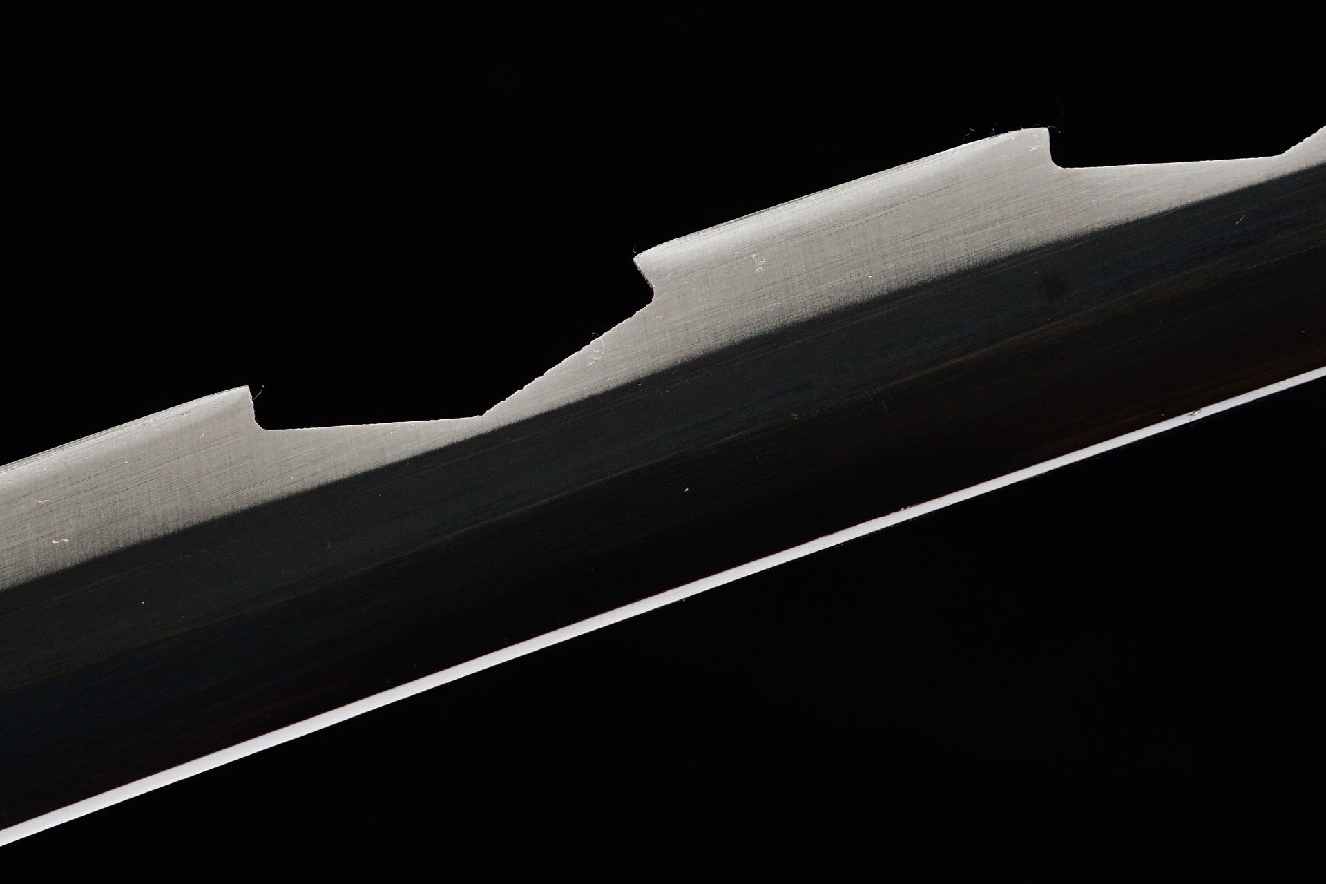Close view of the dark blade with stepped serrated spine profile