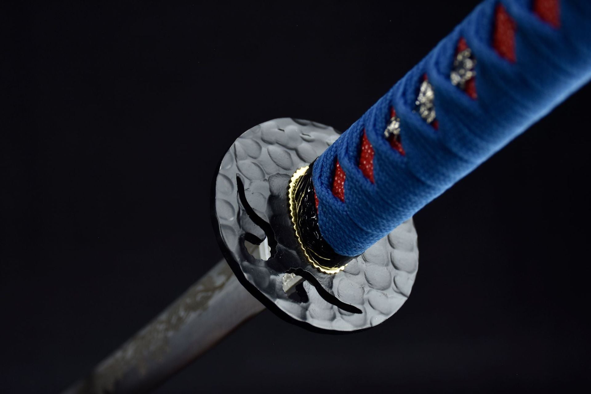 A close-up view of the black round tsuba showcasing its intricate design