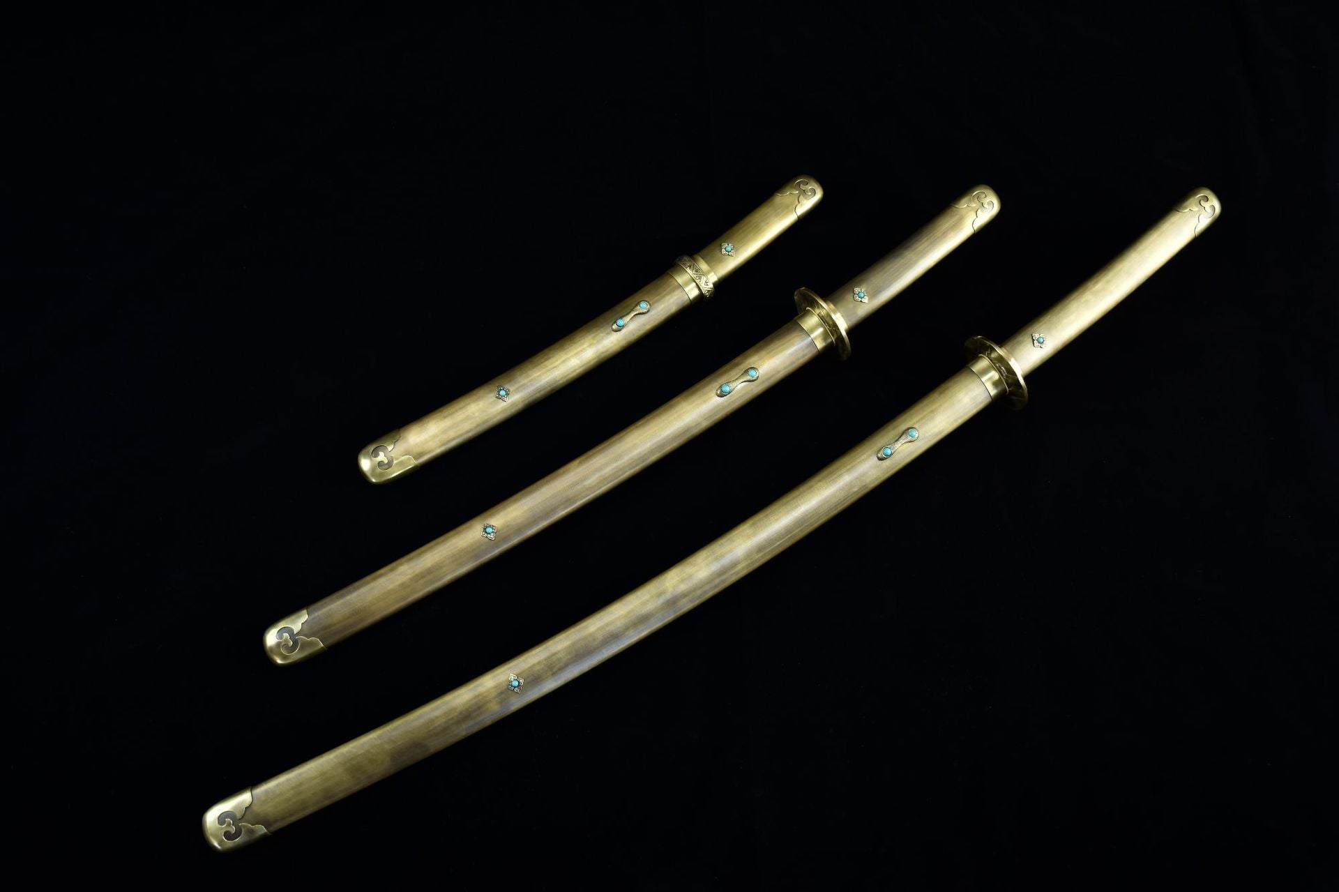 A set of samurai swords featuring copper fittings with brass inlay and turquoise accents.