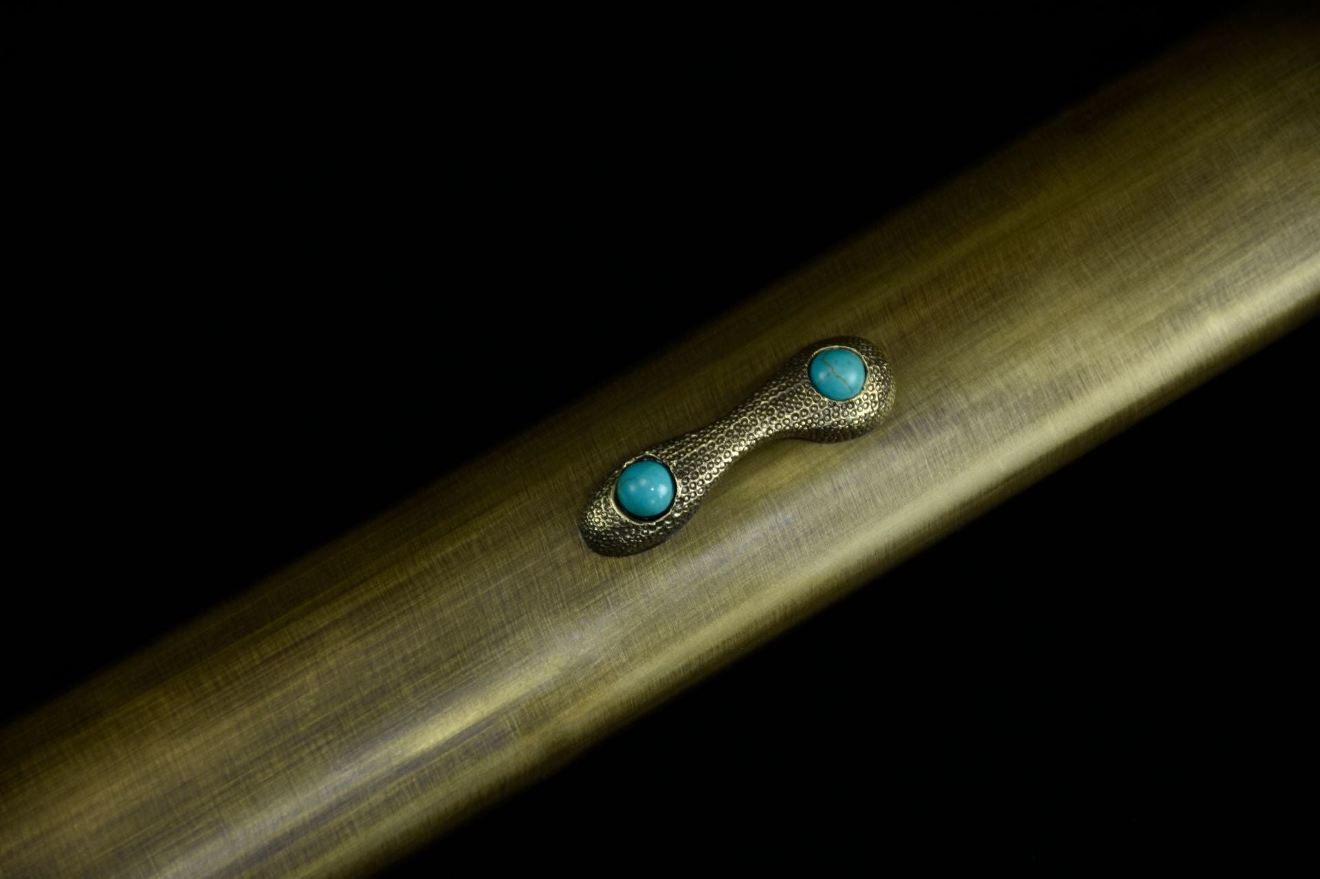 Close-up of the samurai sword kurigata, featuring intricate brass detailing and turquoise inlay.