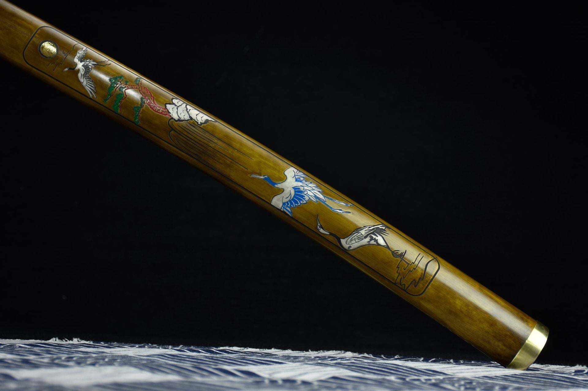 Close-up of the Ichiro Matsuru katana's saya featuring intricate artwork of cranes, clouds, and nature scenes.