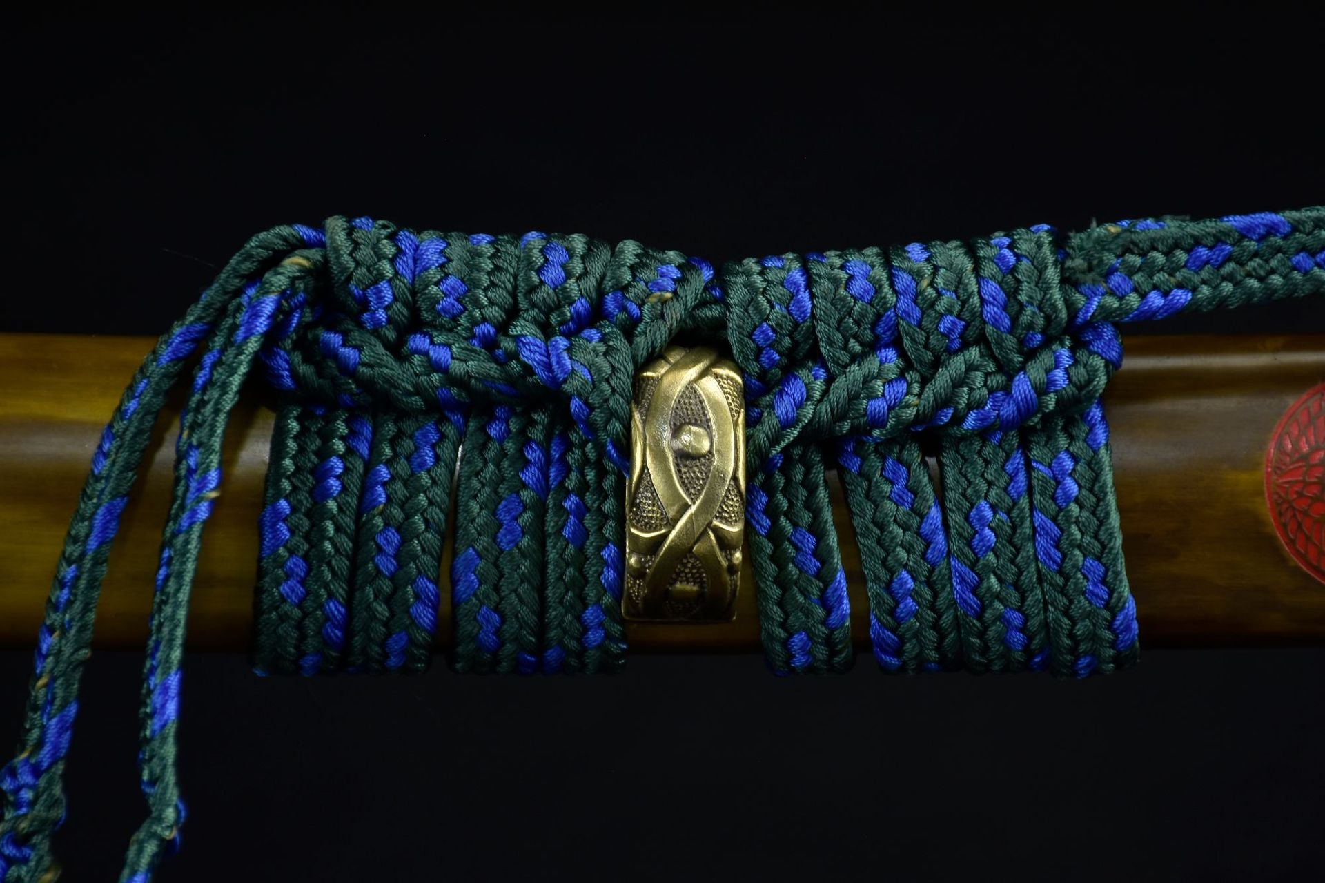 Close-up of the Ichiro Matsuru katana saya featuring an intricate sageo cord in green and blue with a decorative golden knot.