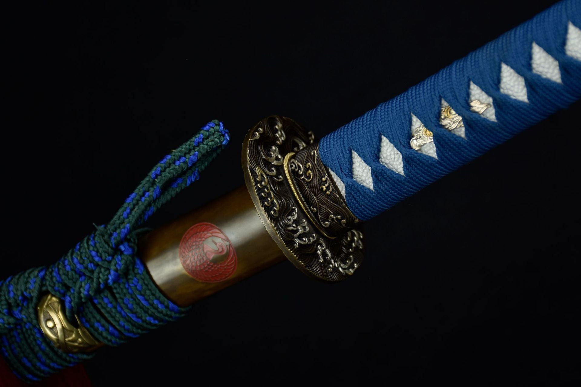 Close-up of the Ichiro Matsuru katana sword's blue wrapped handle, ornate guard, and decorative sheath with a red emblem.
