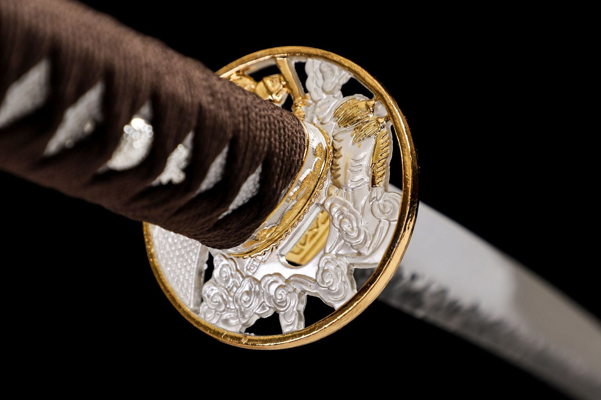 Close-up of an intricately patterned gold and silver tsuba, showcasing fine craftsmanship and detailed design.