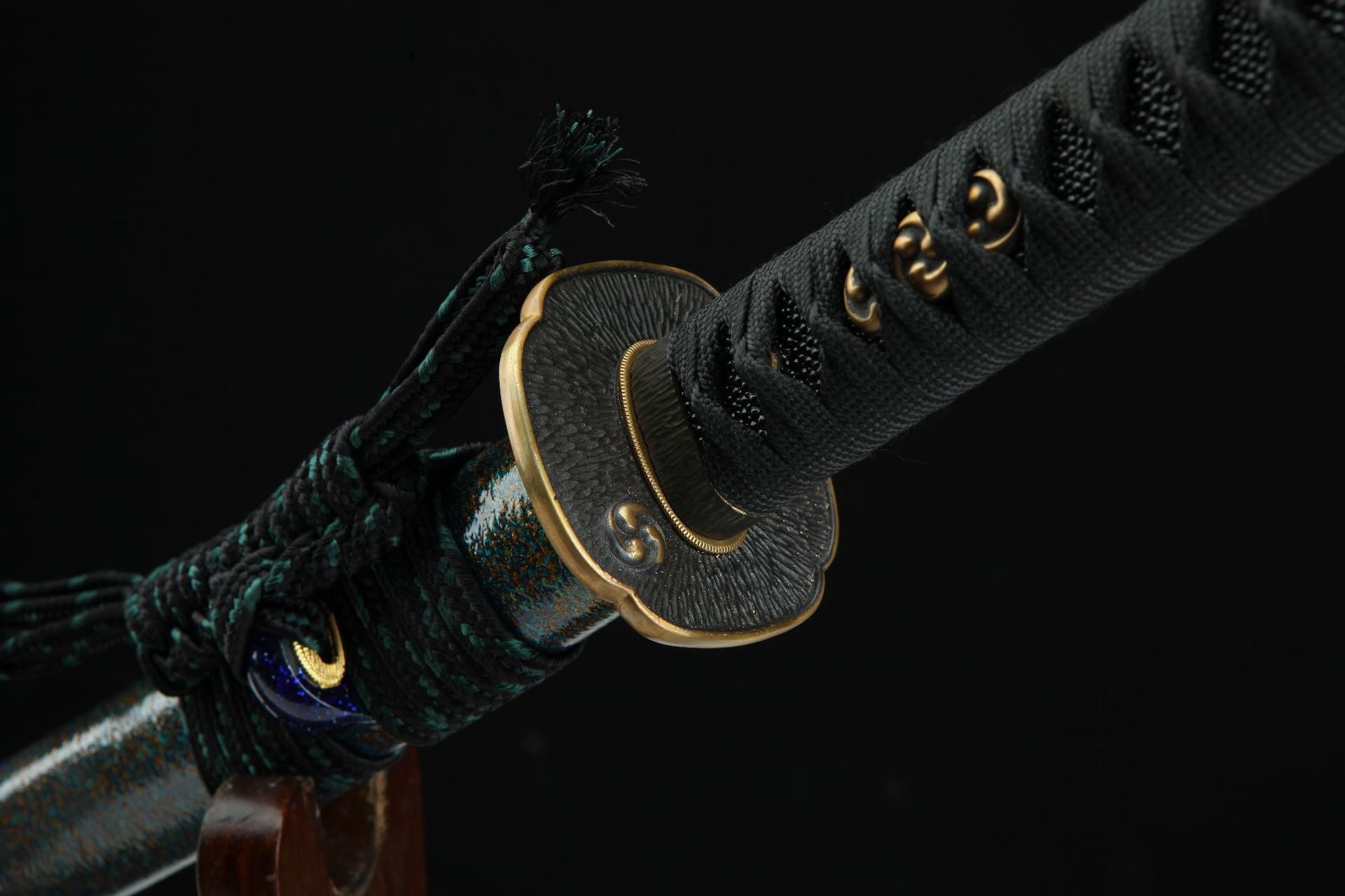 Close-up of the Magatama katana hilt and tsuba featuring a detailed three-tomoe pattern.