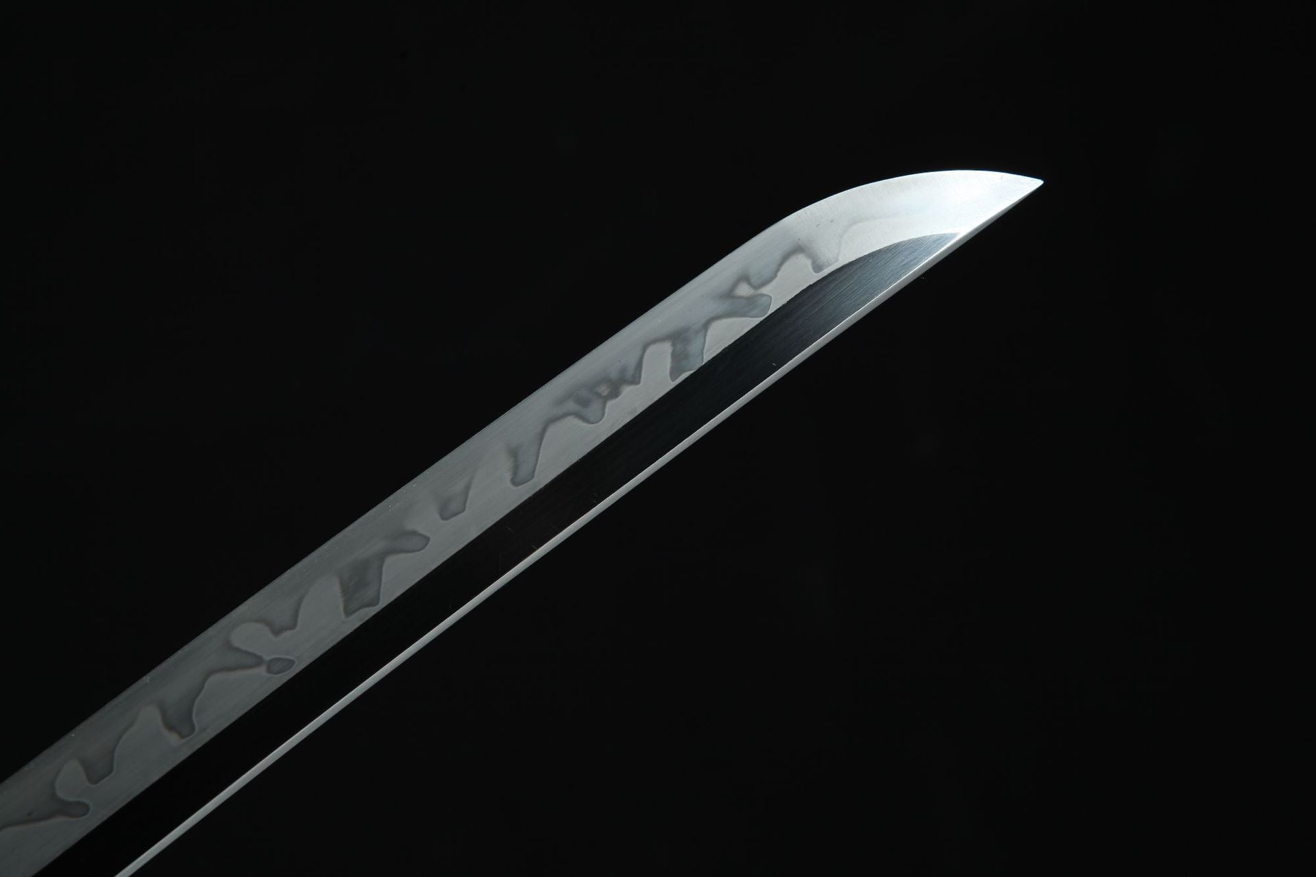 Close-up of Magatama katana kissaki with clay-tempered hamon pattern on T10 steel blade.