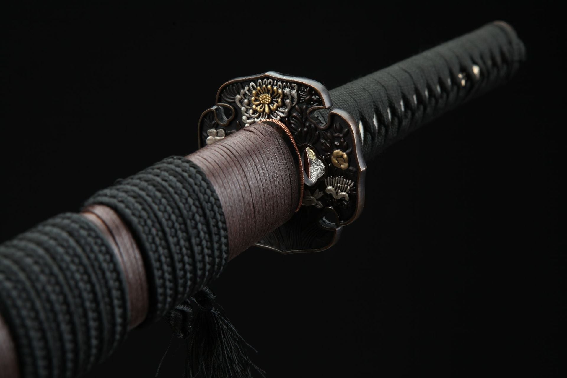 Close-up of the reverse side of a tri-color daisy tsuba, showcasing intricate engraving details
