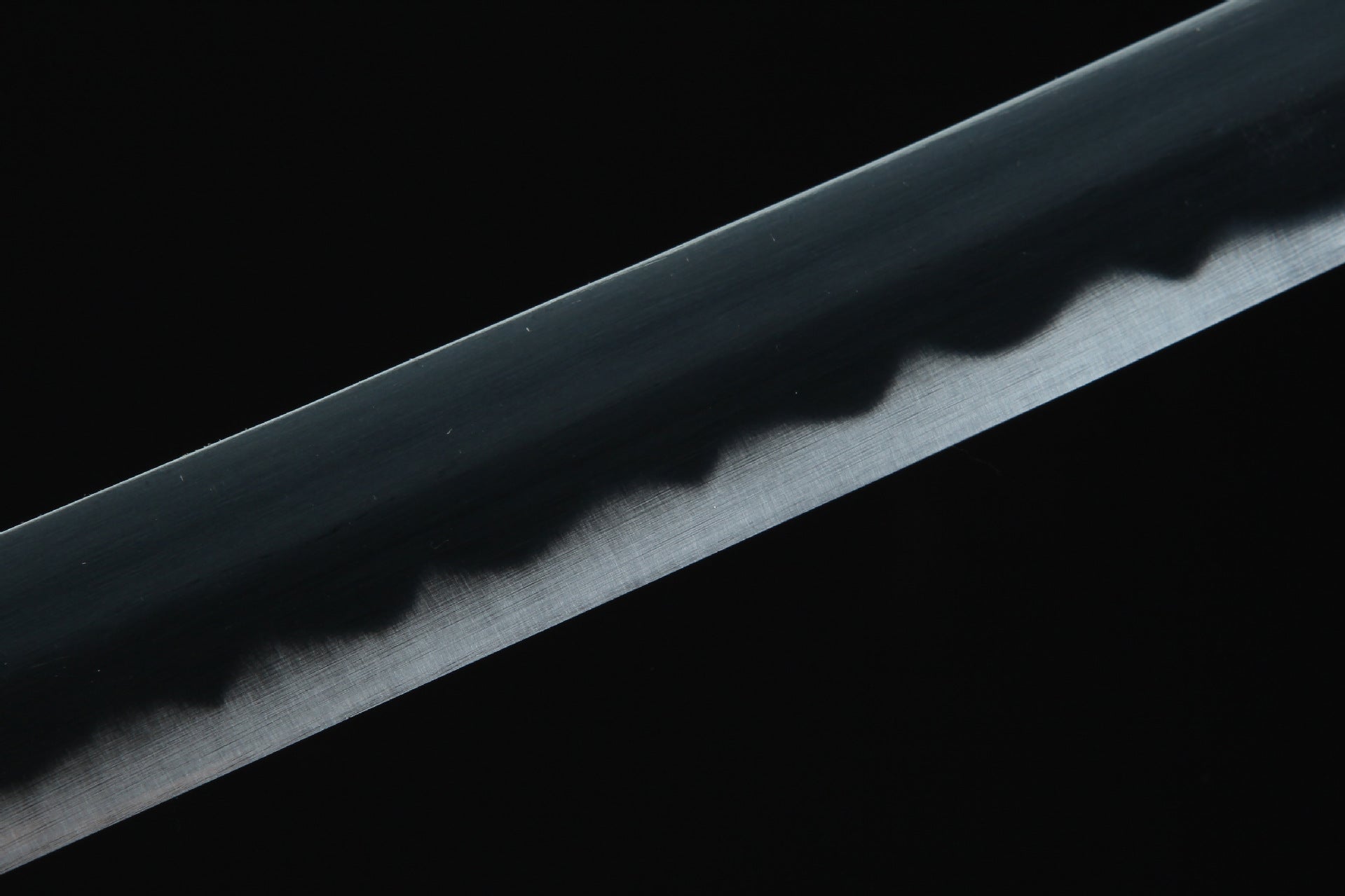 Close-up of Sandai Kitetsu sword blade, featuring a white edge and black body.