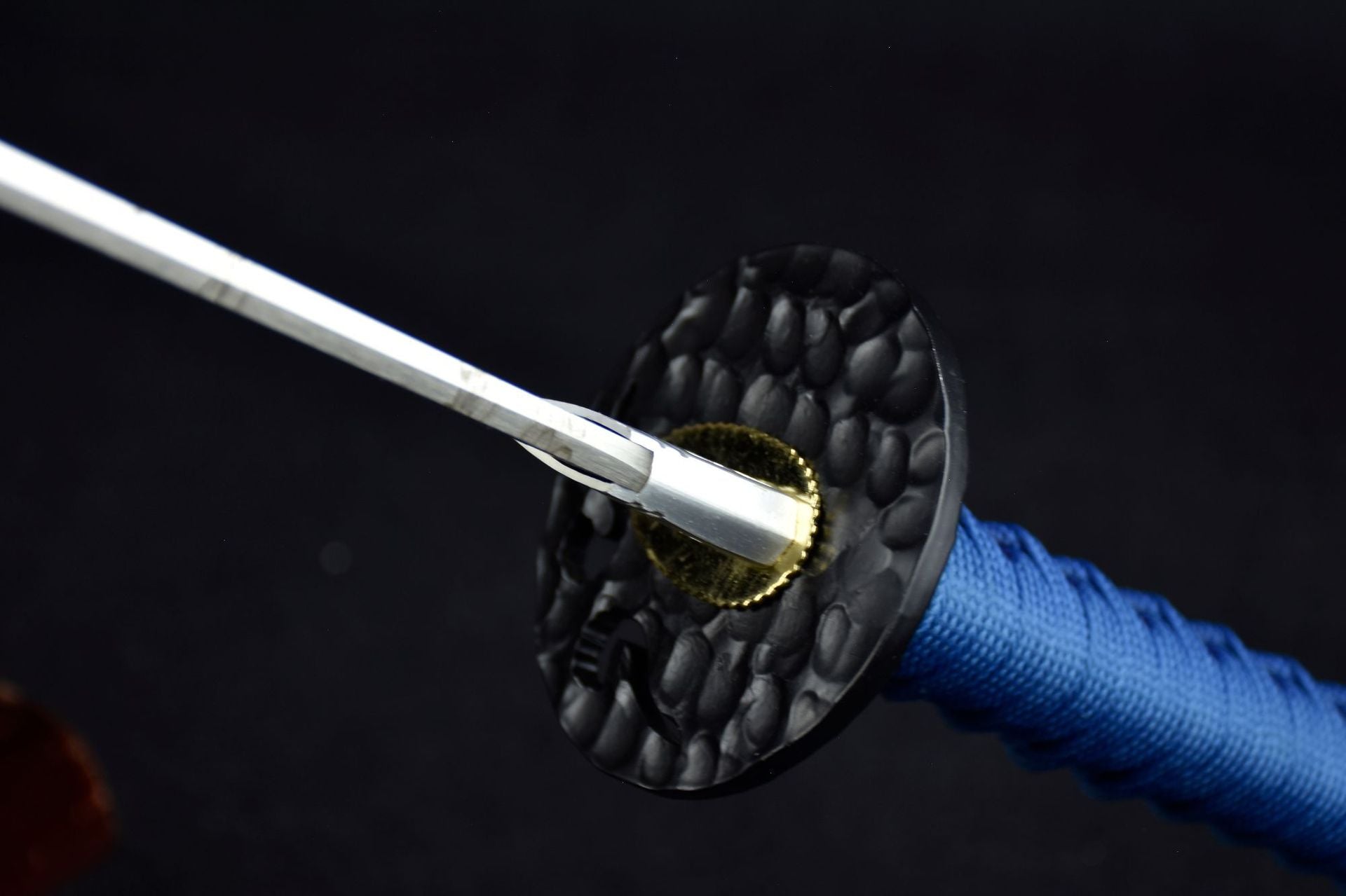 A side close-up view of the black round tsuba highlighting its detailed craftsmanship