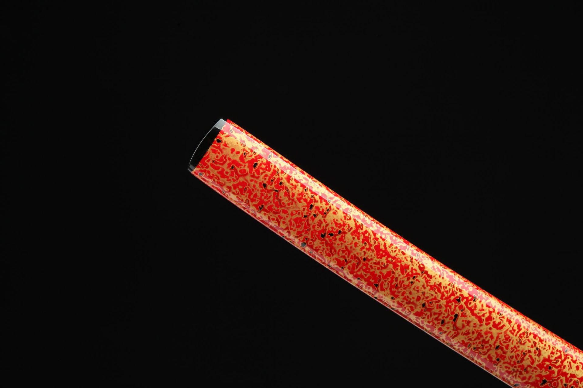 Close-up view of the tip of the red lacquer saya, showcasing the unique speckled design.