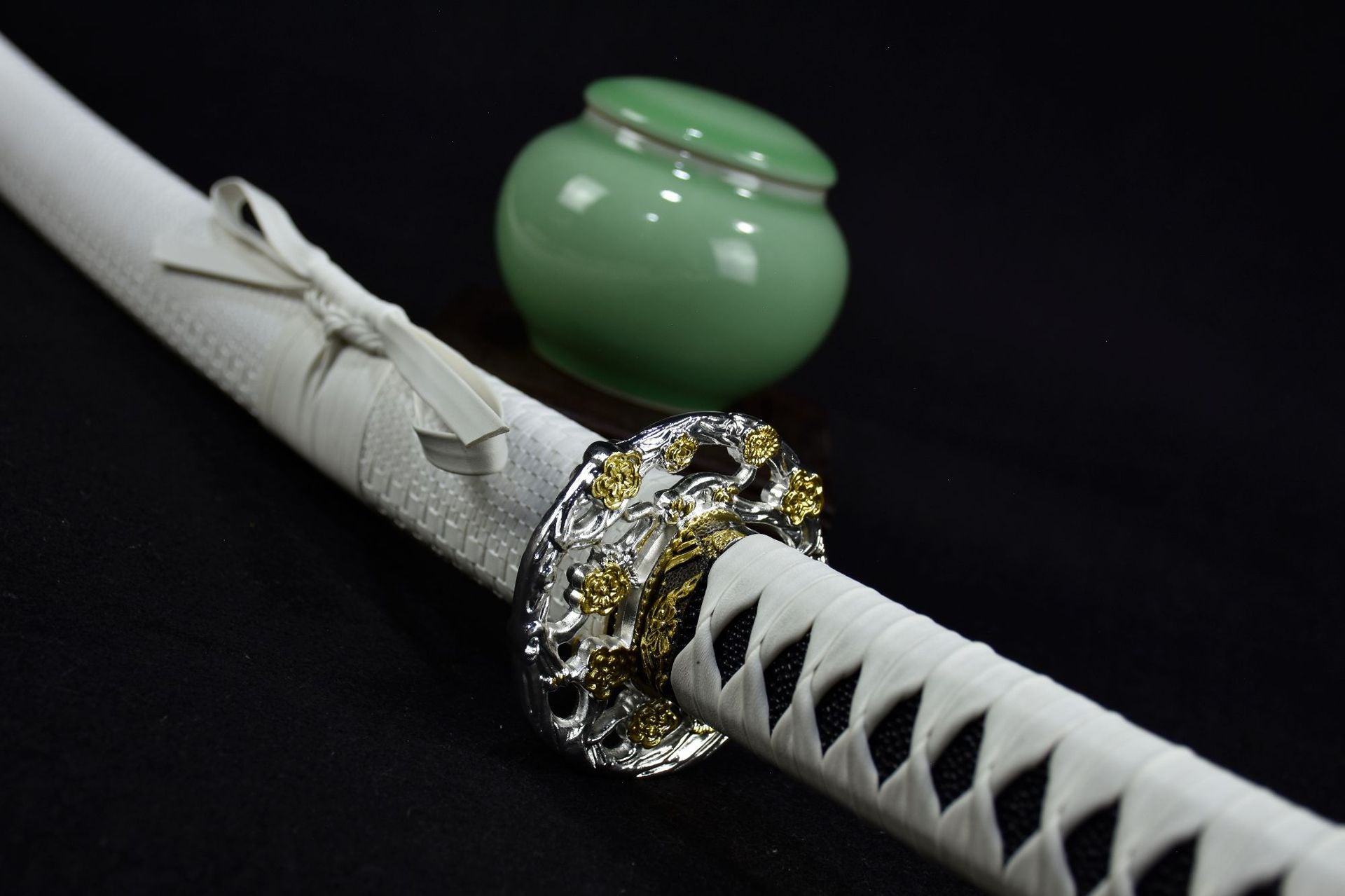 A white katana featuring a detailed silver plum blossom tsuba
