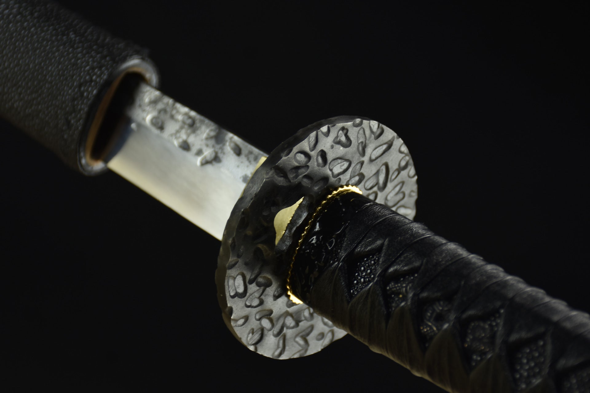 A black circular tsuba, the guard of a samurai sword.