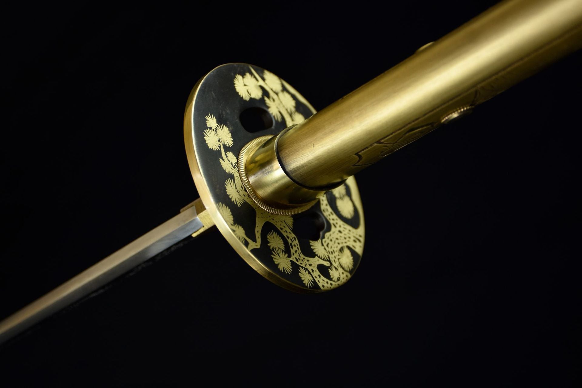 Close-up of a katana featuring a brass tsuba with intricate sakura floral engraving.