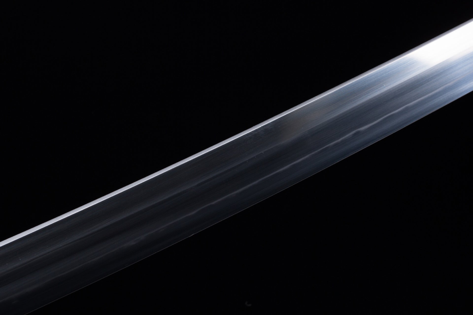 A close-up view of a katana blade with a hand-polished finish, showcasing intricate details and masterful craftsmanship.