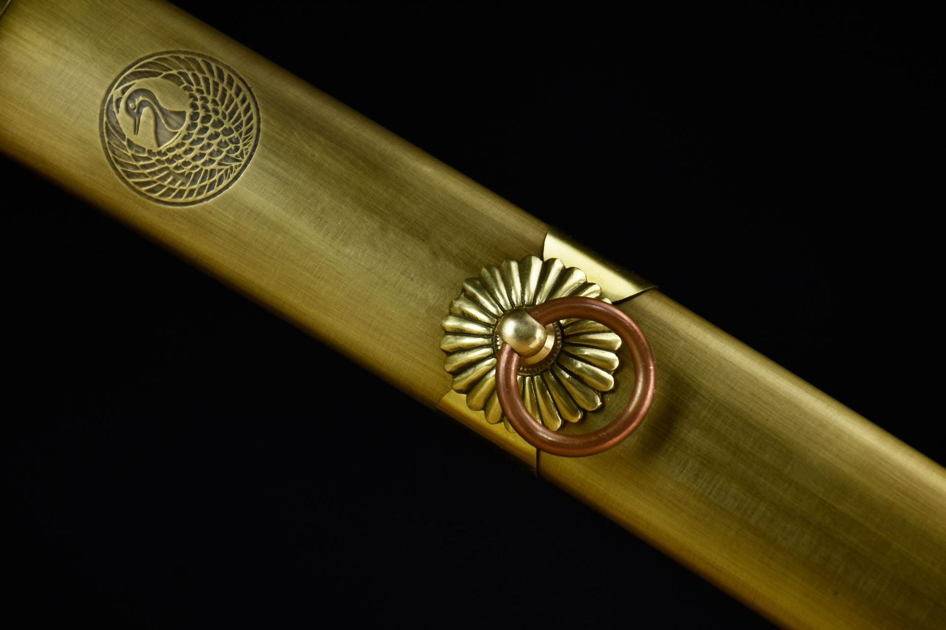 Close-up details of a copper katana scabbard intricately engraved with a crane motif.