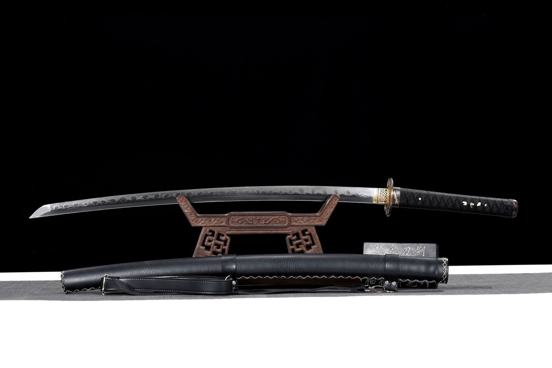 A hand-forged katana with a dragonfly motif, paired with a sleek black leather scabbard, showcasing traditional Japanese craftsmanship.