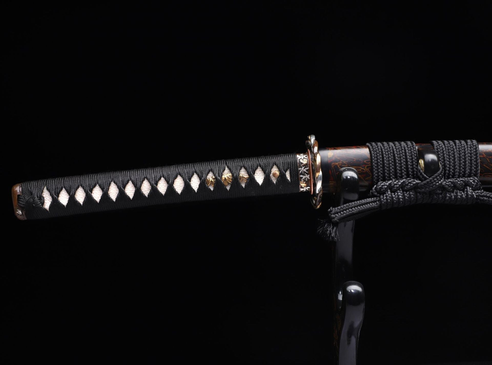Close-up of Kiri-giri katana’s handle featuring gold Menuki and black ito.