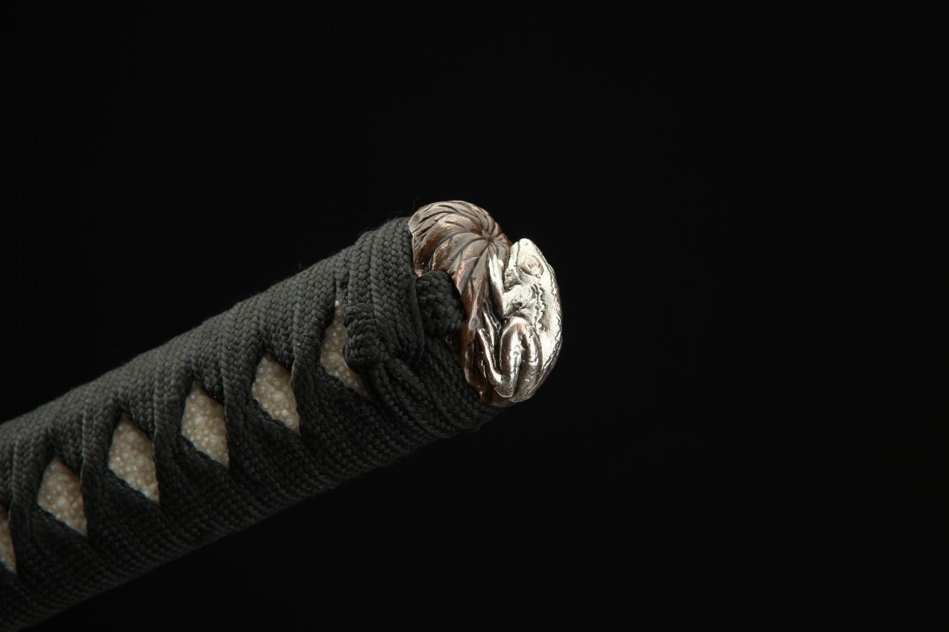 Close-up view of the Lotus katana's kashira featuring a carved toad on a lotus leaf.