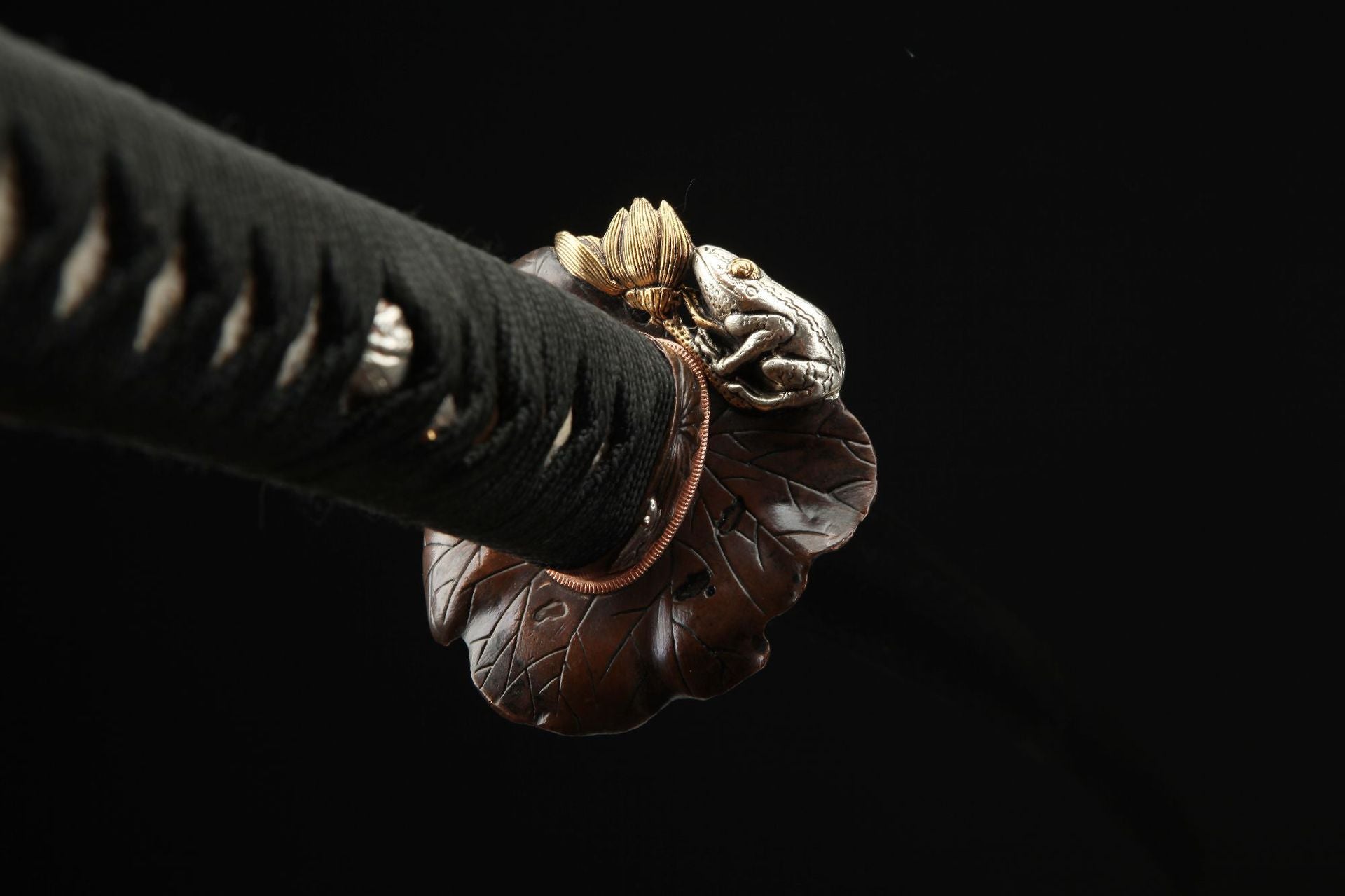 Close-up of the Lotus katana's tsuba designed as a lotus leaf with a toad.
