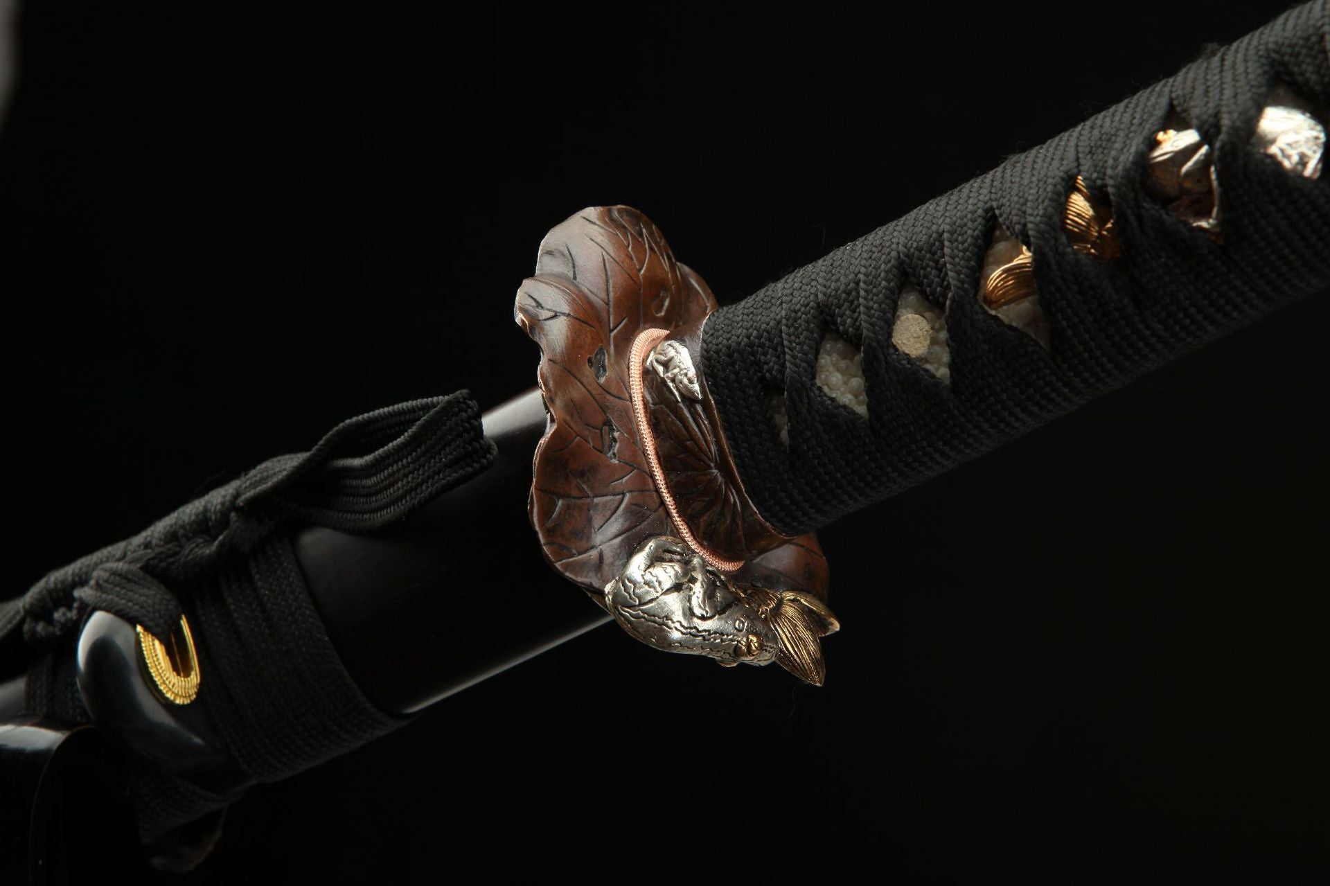 Side view of the Lotus katana's tsuba, depicting a lotus leaf and toad carving.