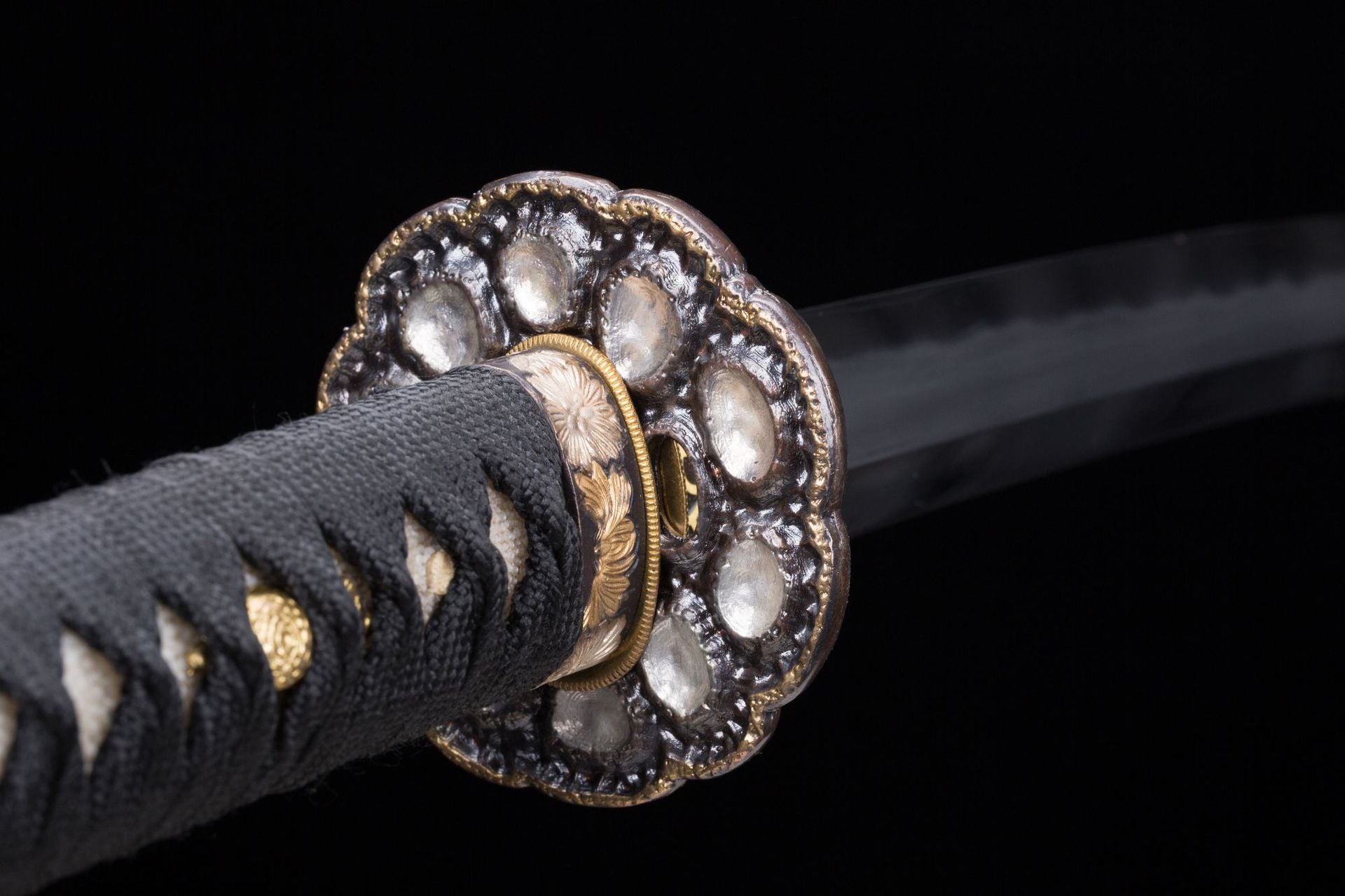 Close-up of a round tsuba on a Meditation katana featuring gold details and intricate design.
