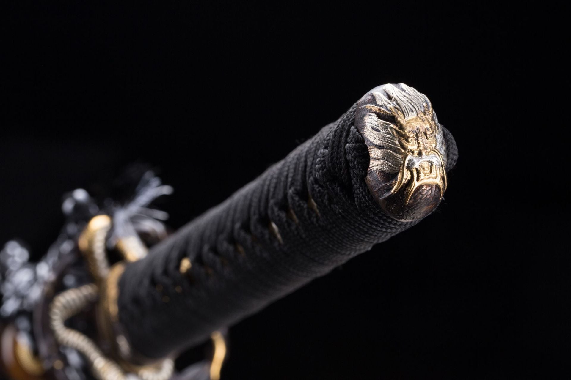 Close-up view of the Orochi katana's kashira featuring a detailed loong design in gold.