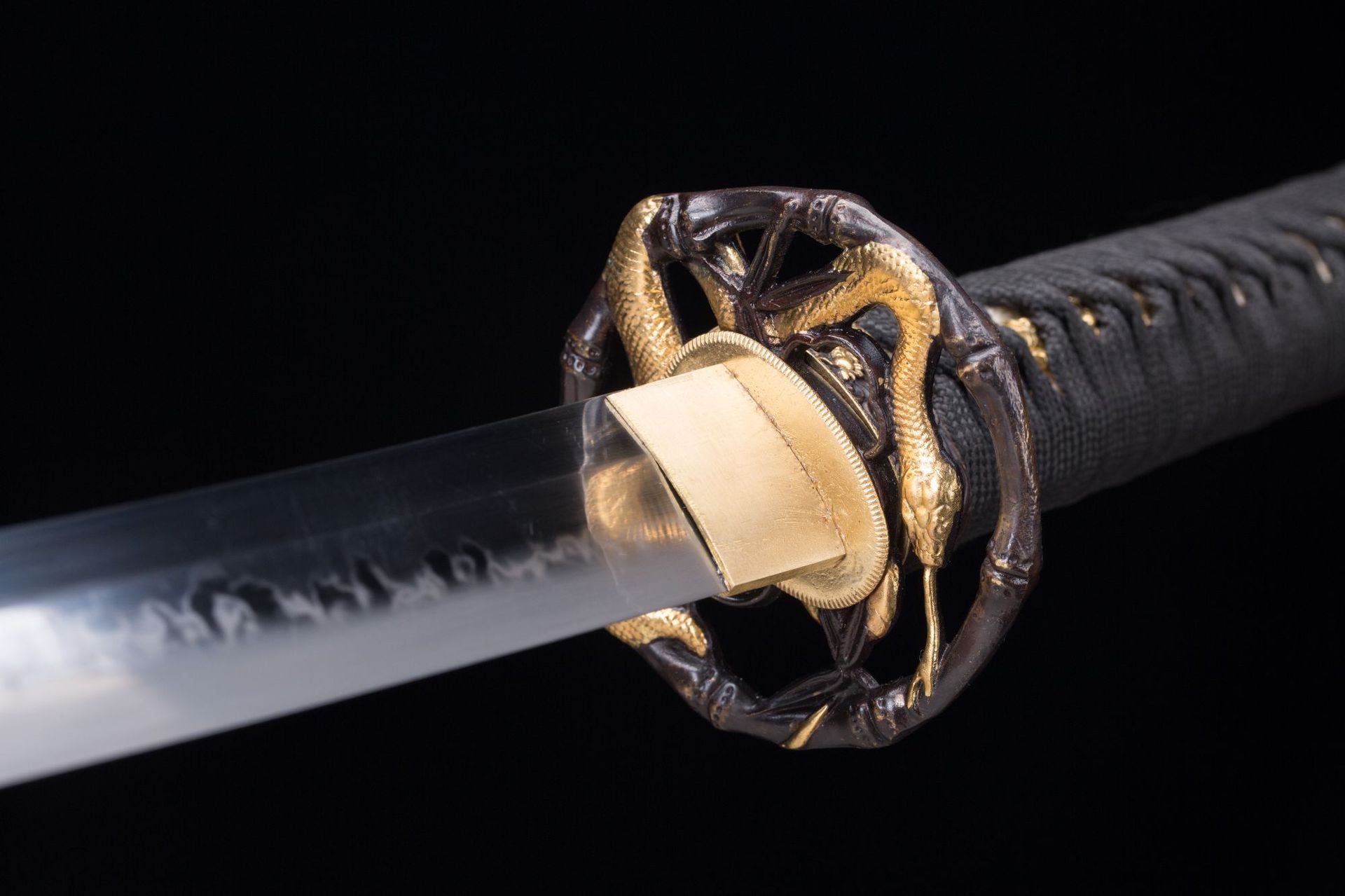 Close-up of Orochi katana's handle showing the orochi-etched tsuba and intricate grip details.