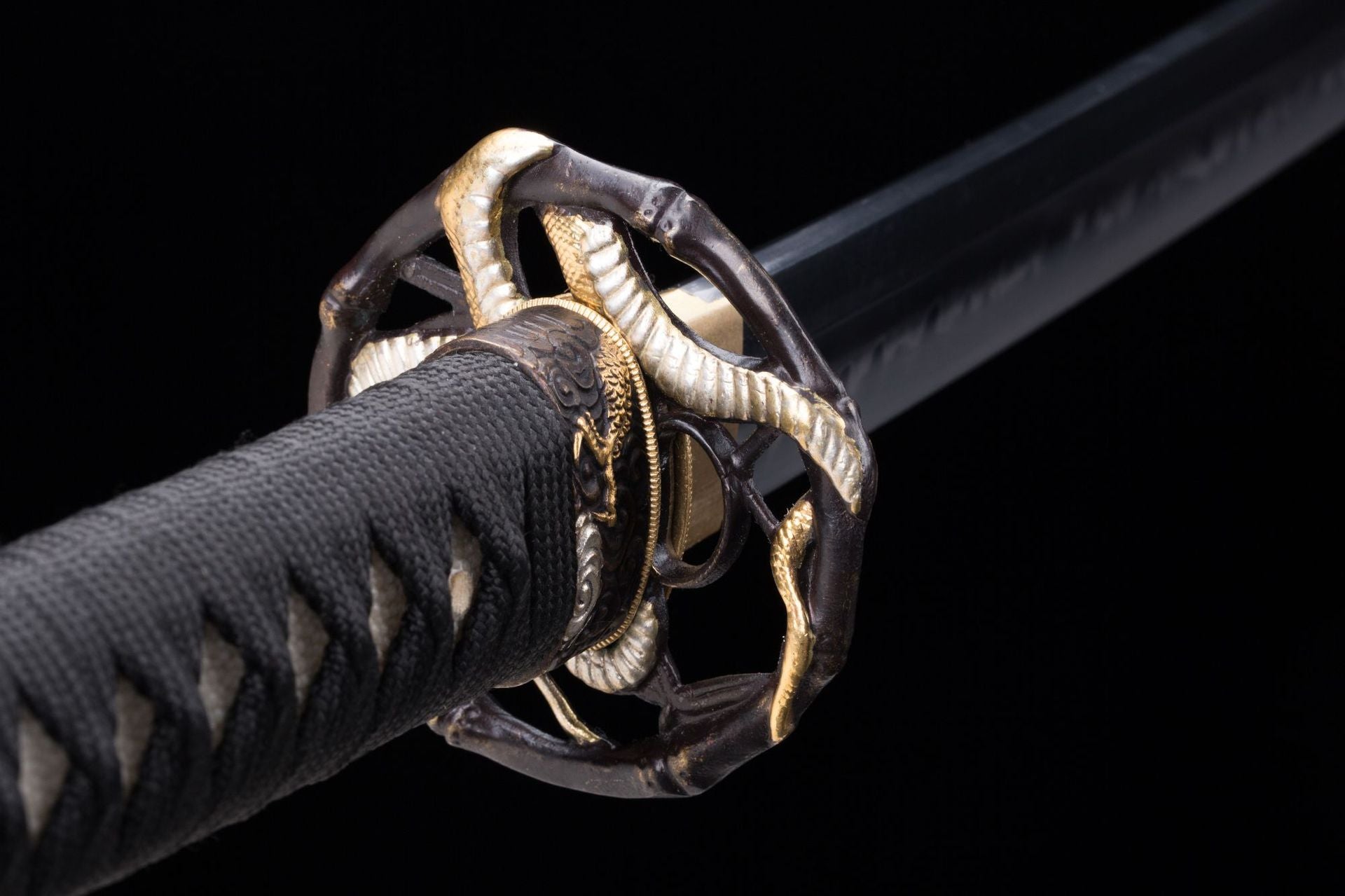 Detailed close-up of Orochi katana's tsuba with a golden orochi design wrapped around.