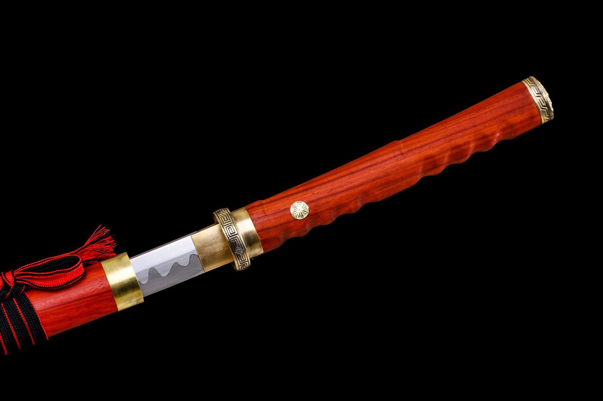 Closeup of a katana tsuka made of red rosewood, gold habaki, and polished blade with a wavy hamon pattern.