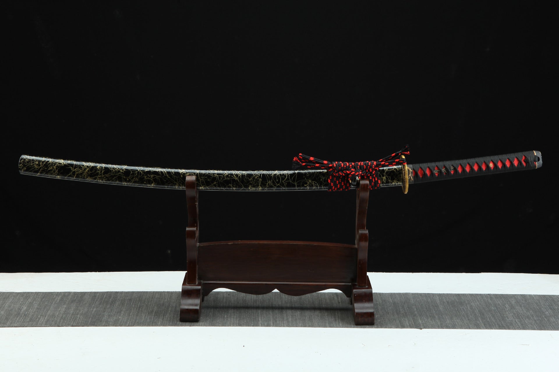 Full view of the Sakura katana, showcasing the black and gold saya with intricate crack design, wrapped handle, and red sageo knot.