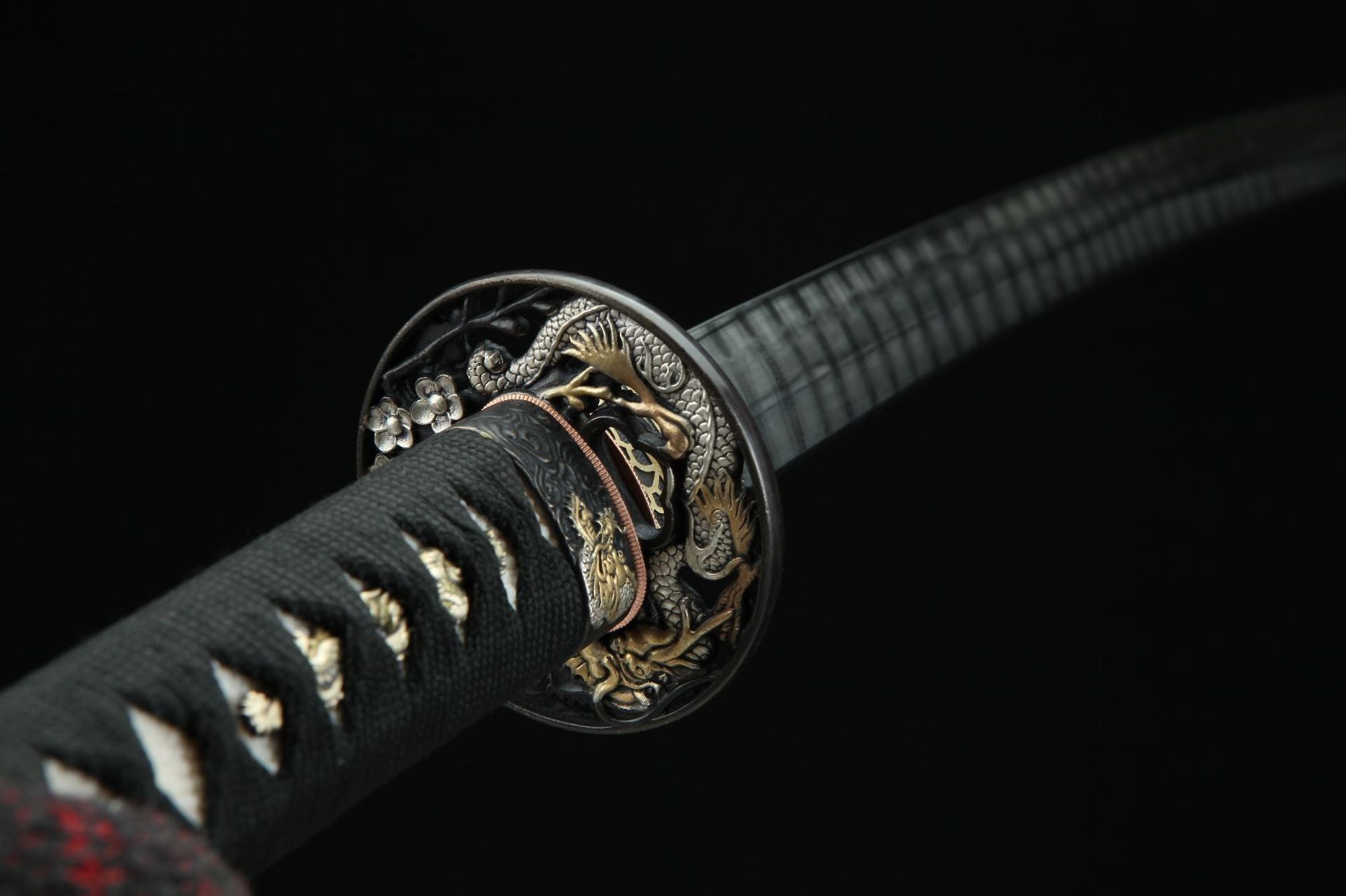 Close-up of sakura ryu katana tsuba featuring intricate sakura and ryu carvings in a circular design.