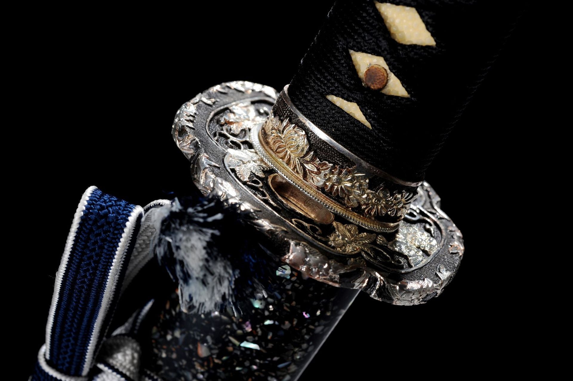 Side view of a silver-plated, engraved katana guard.