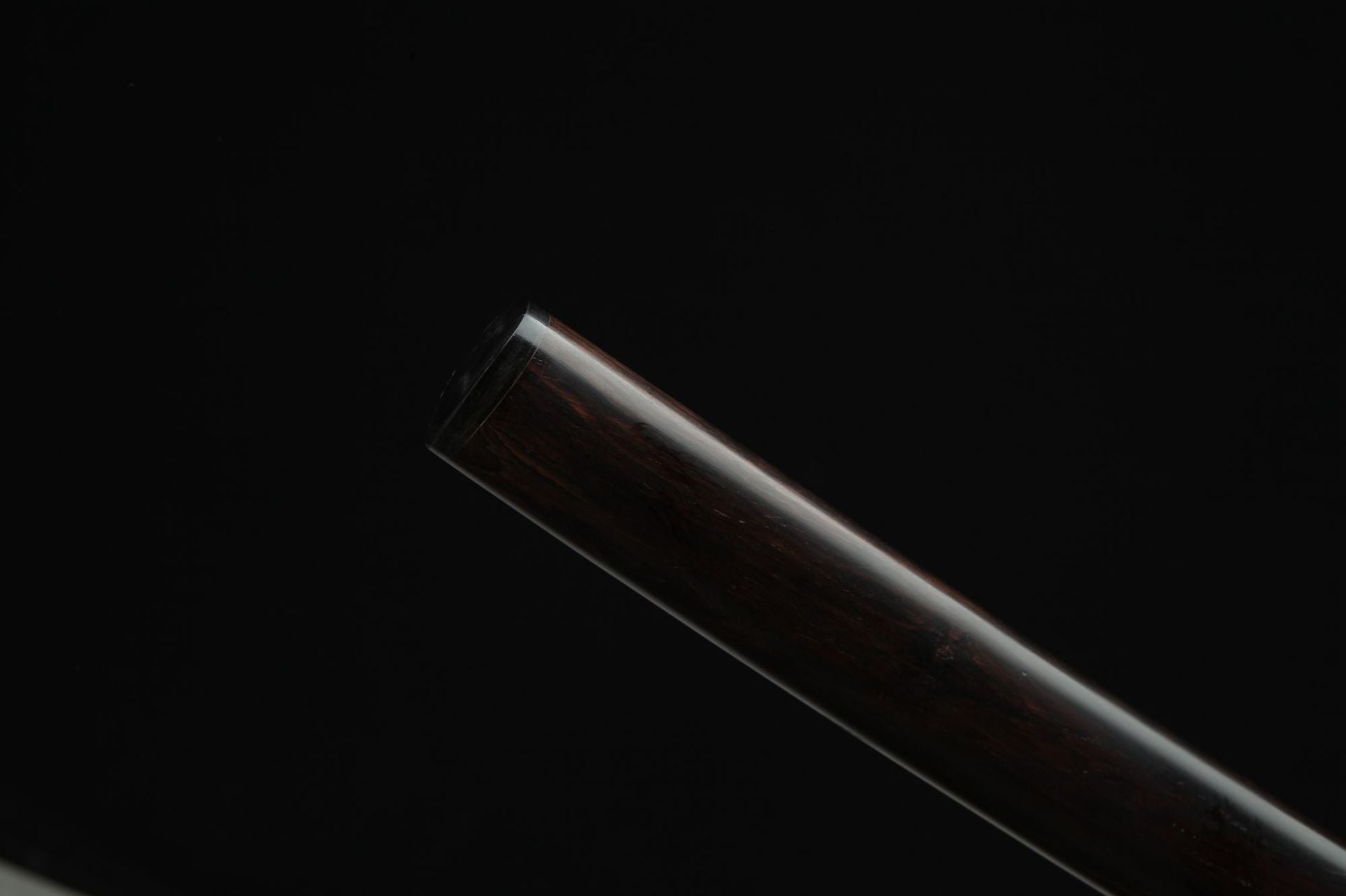 Close up of the Sunflower Ebony samurai sword scabbard tip showcasing a polished ebony wood finish
