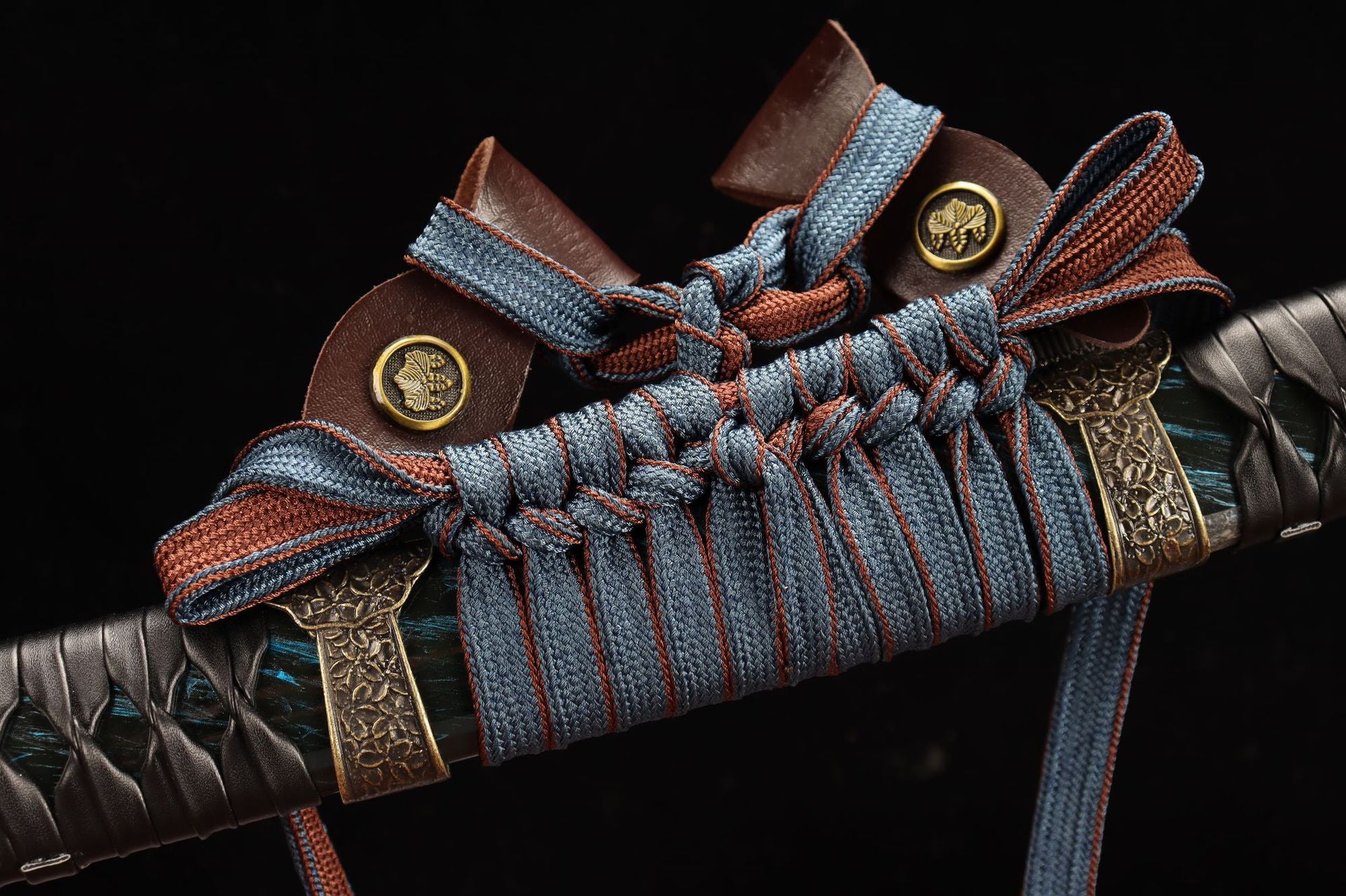Closeup of a tachi sageo knot with blue and red cord, featuring gold accents and intricate craftsmanship.