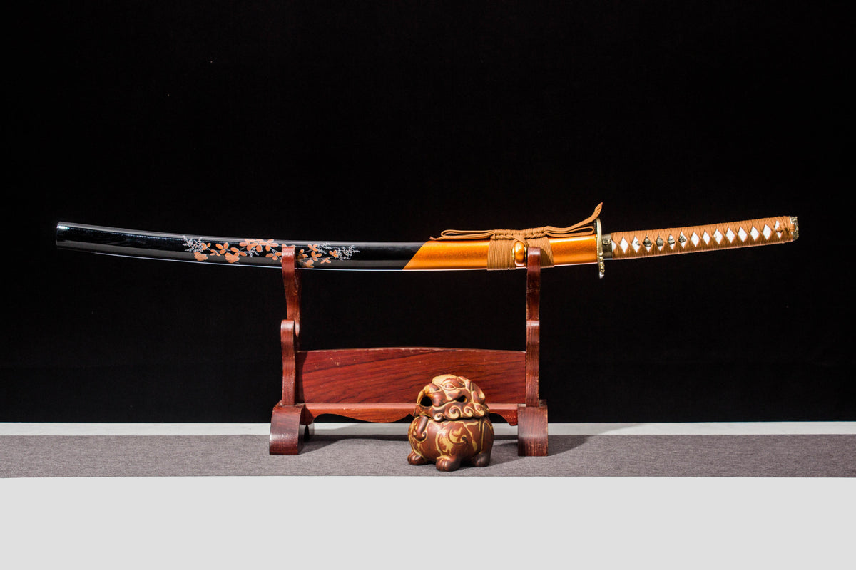 Sakura in Gold Katana displayed sheathed with an orange handle and black saya with floral detail