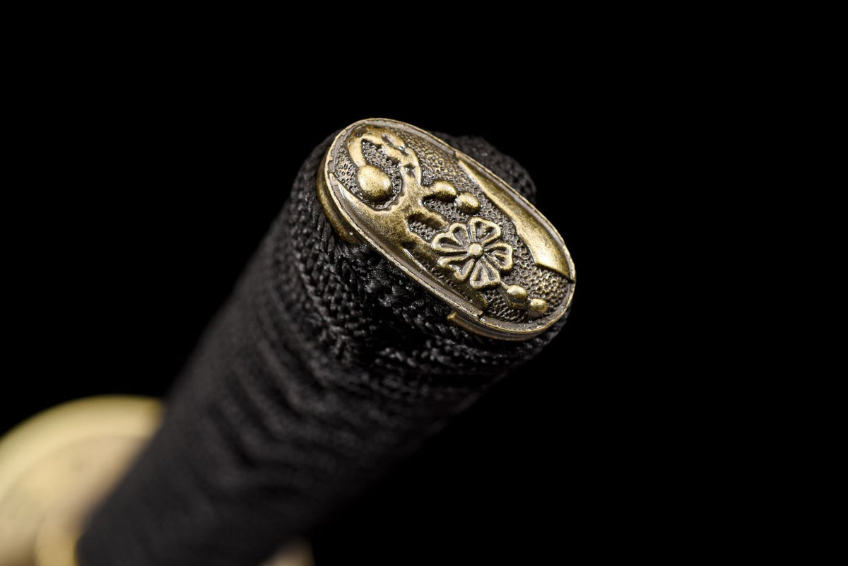 Antique-gold-tone floral kashira at the end of the black wrapped katana handle