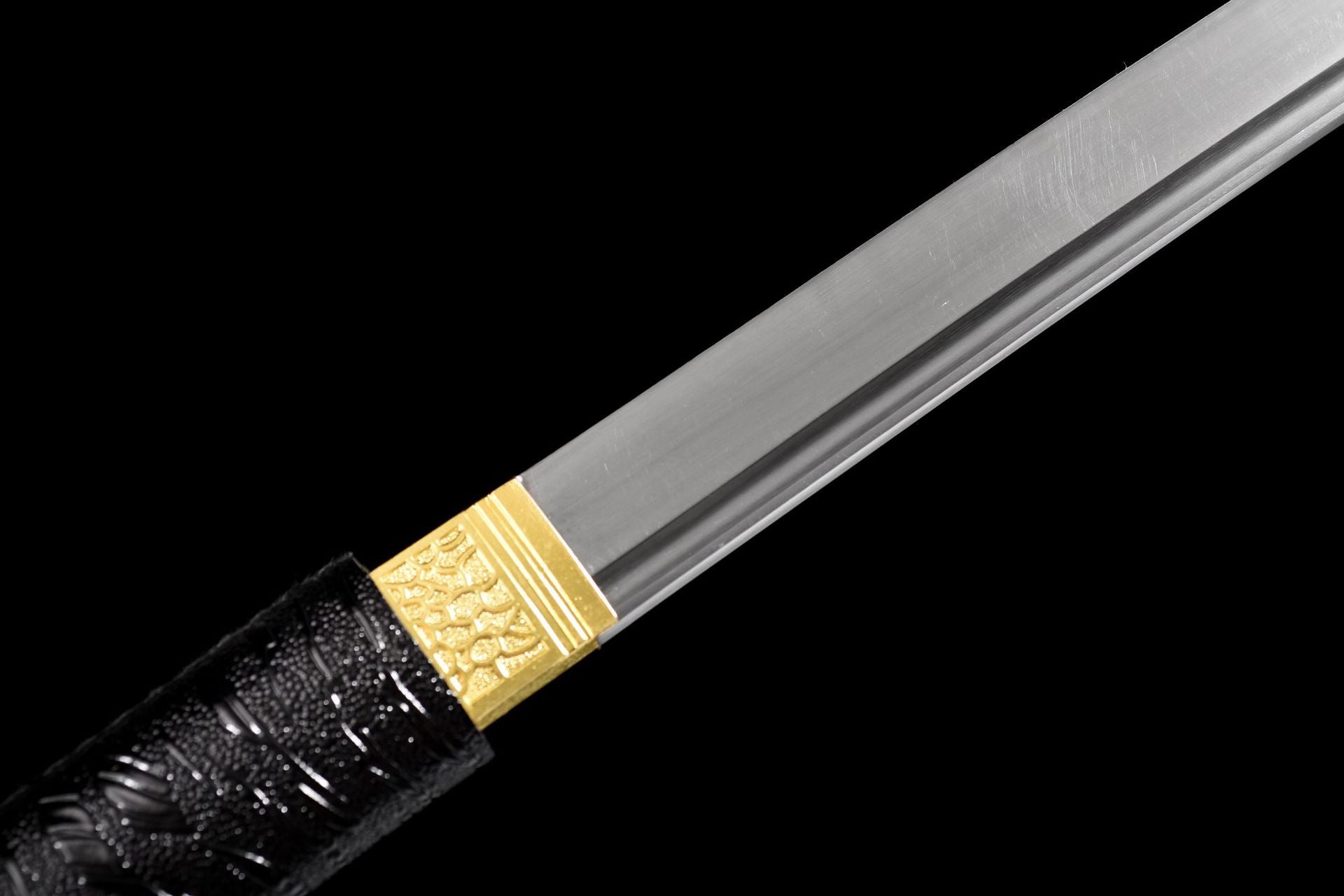 Dual-groove manganese steel blade beside the gold-tone habaki