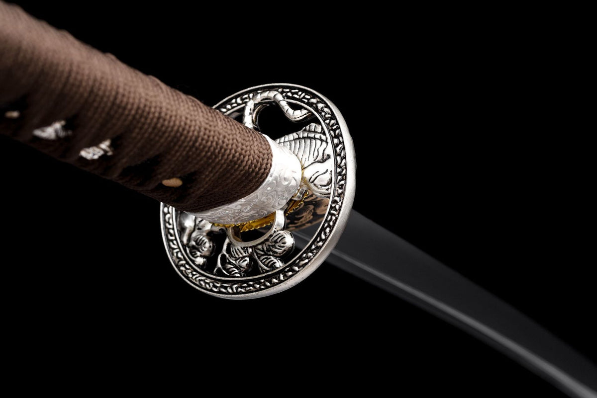 Reverse of the tiger-and-foliage tsuba beside the brown tsuka