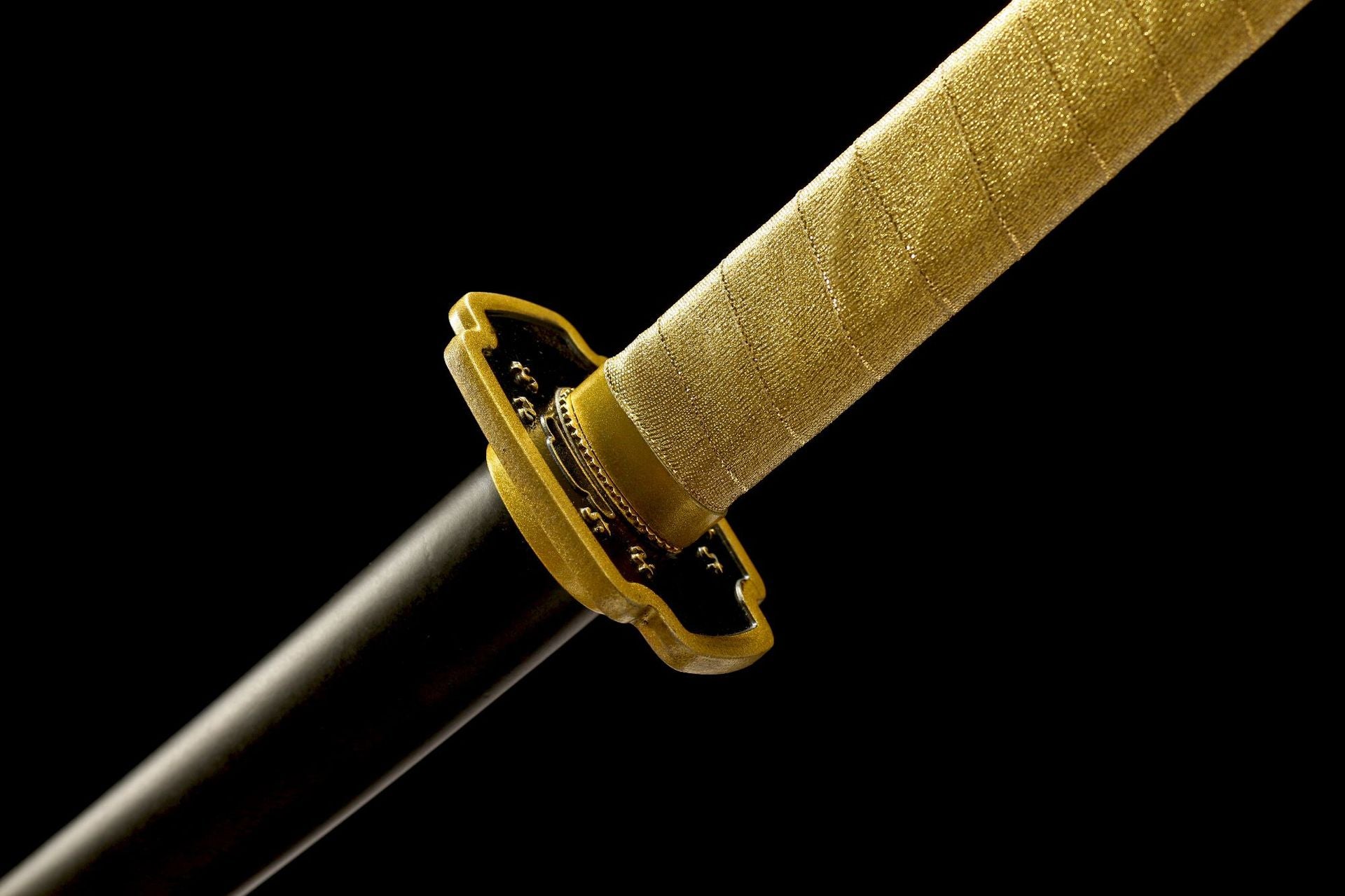 Black-and-gold Yoriichi Nichirin sword guard beside the gold-wrapped handle