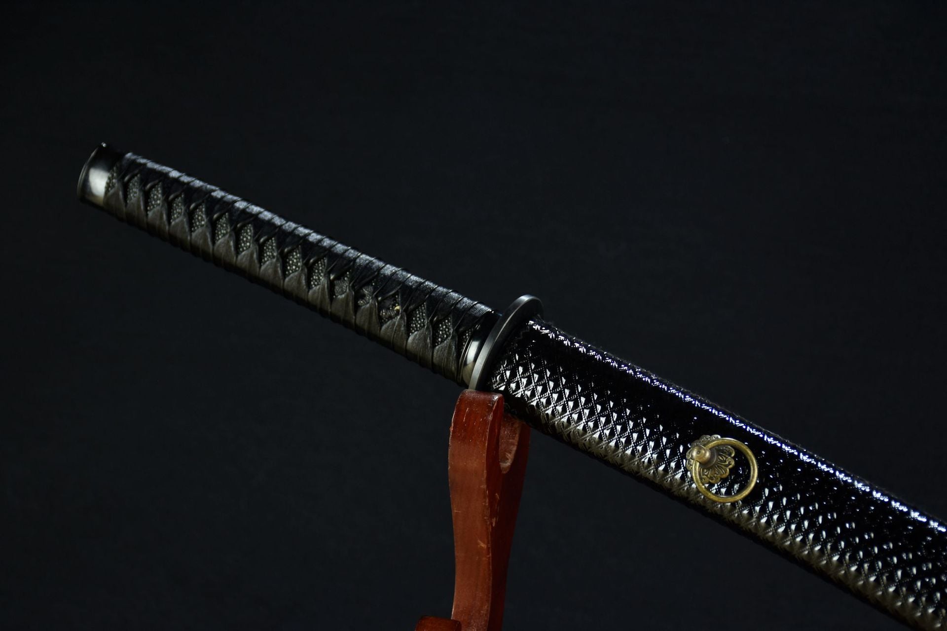 A black samurai sword handle, tsuba, and scabbard displayed together