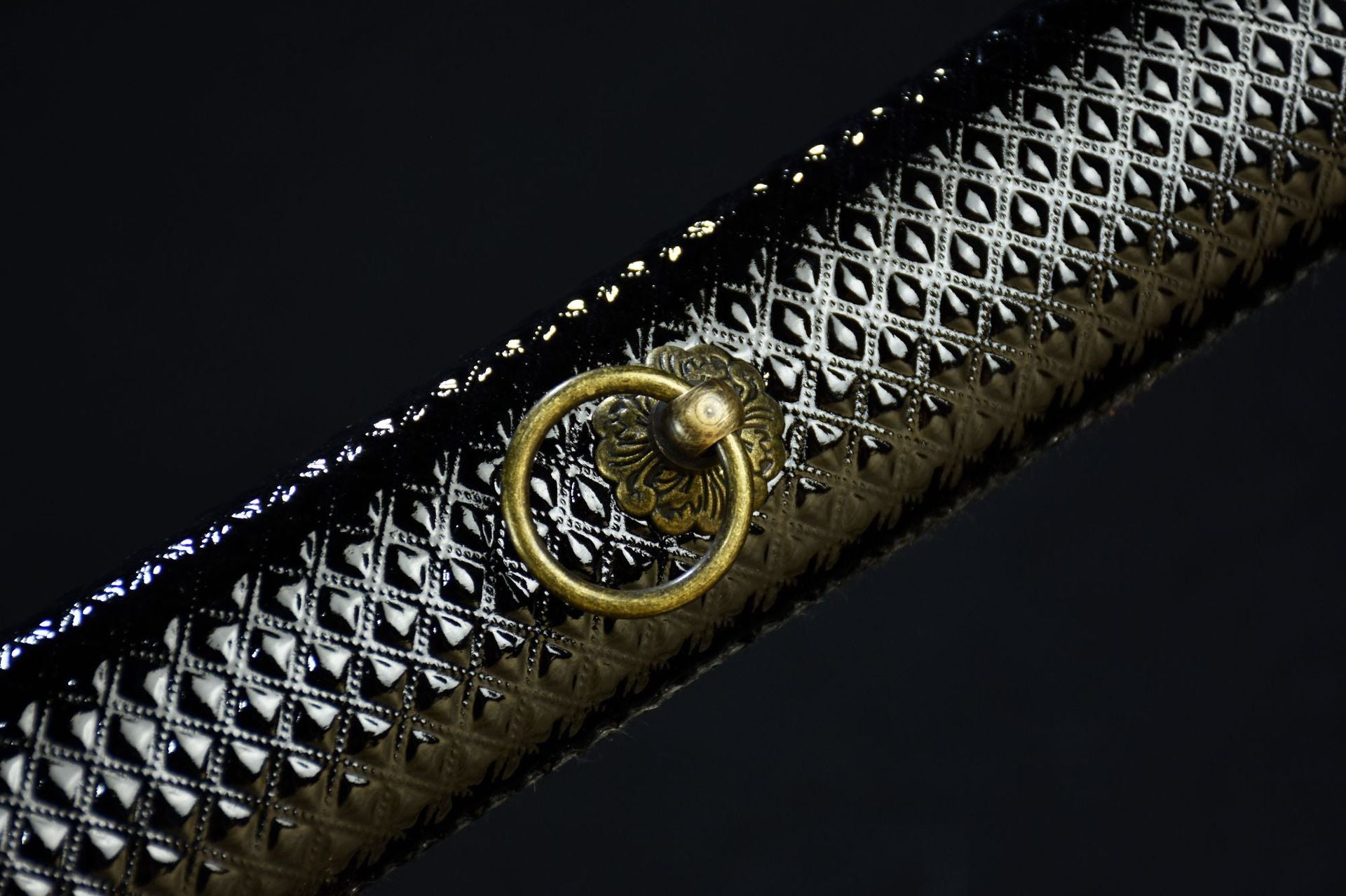 A close-up view of a black faux leather patterned scabbard