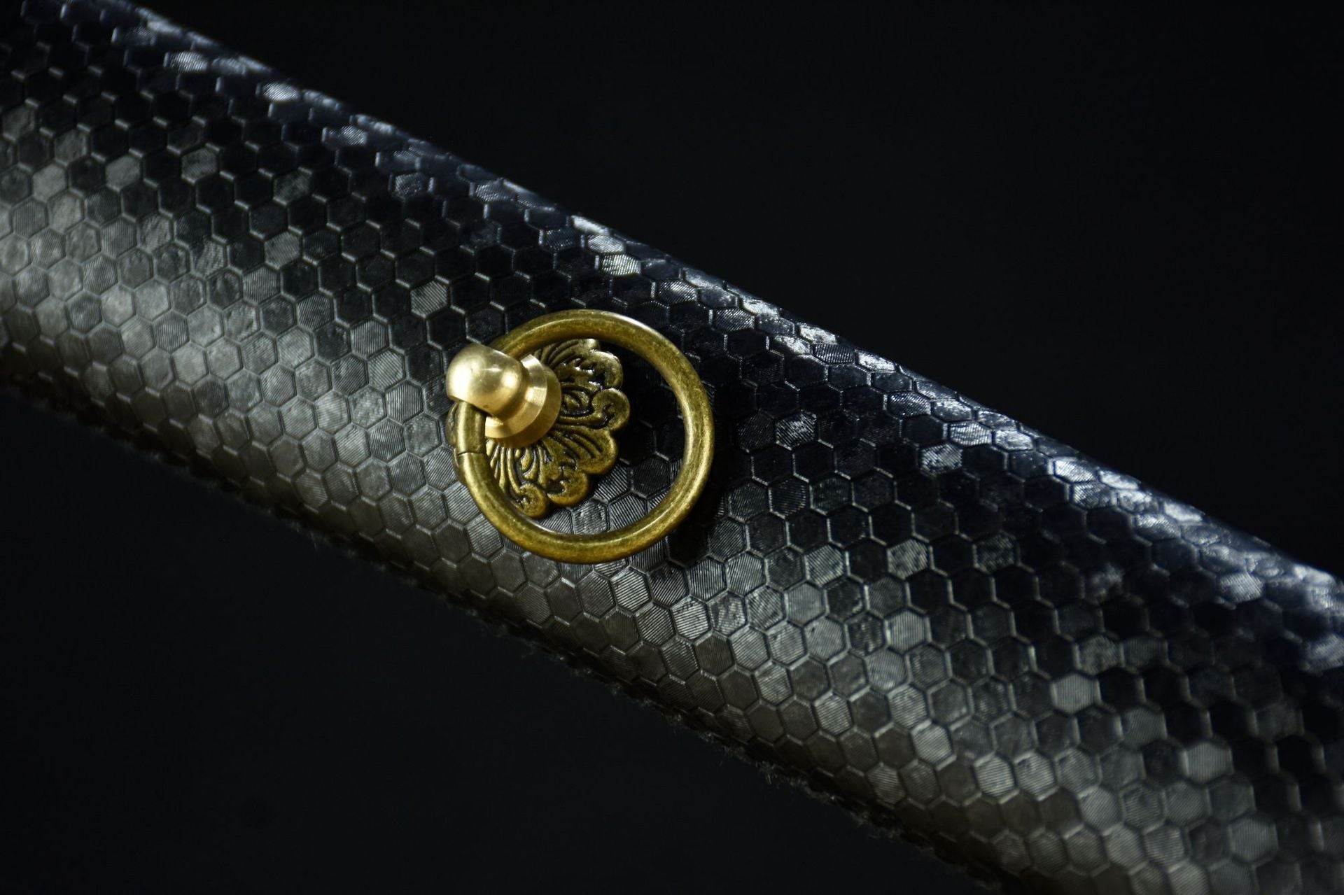 A detailed view of a black faux leather scabbard with a diamond pattern