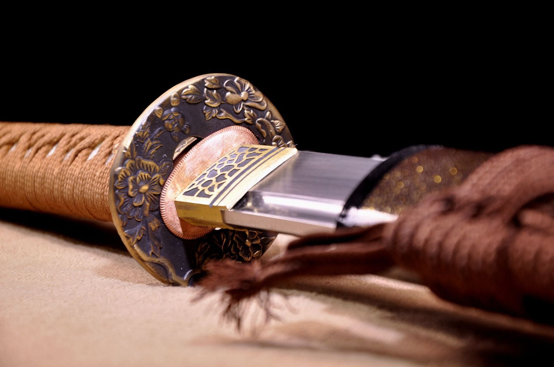A detailed view of the Fallen Sakura samurai sword's guard with floral engravings, along with the polished blade and decorative sheath.