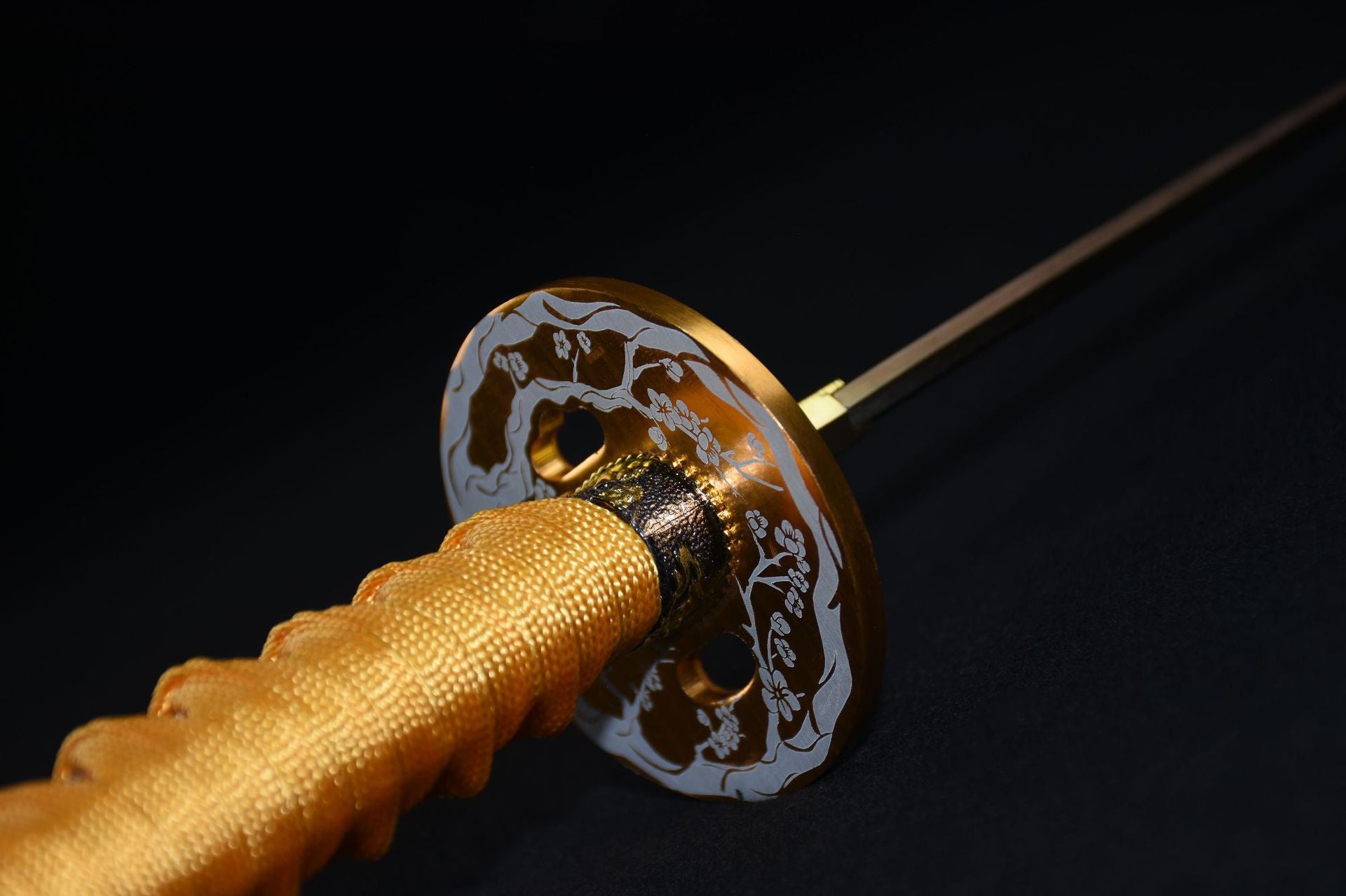 A gold round tsuba on a katana featuring a sakura design