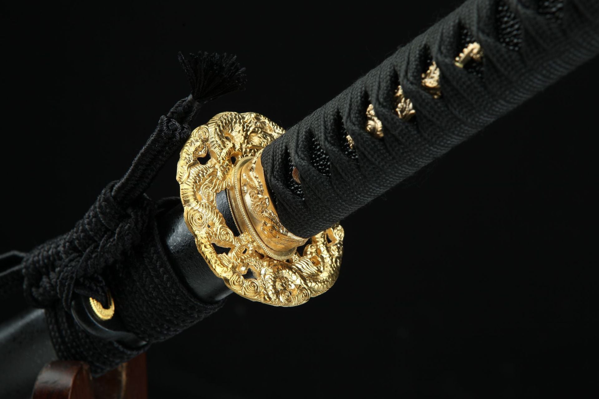 Close-up of the Golden Loong samurai sword's golden guard with dragon engravings and black wrapped handle.