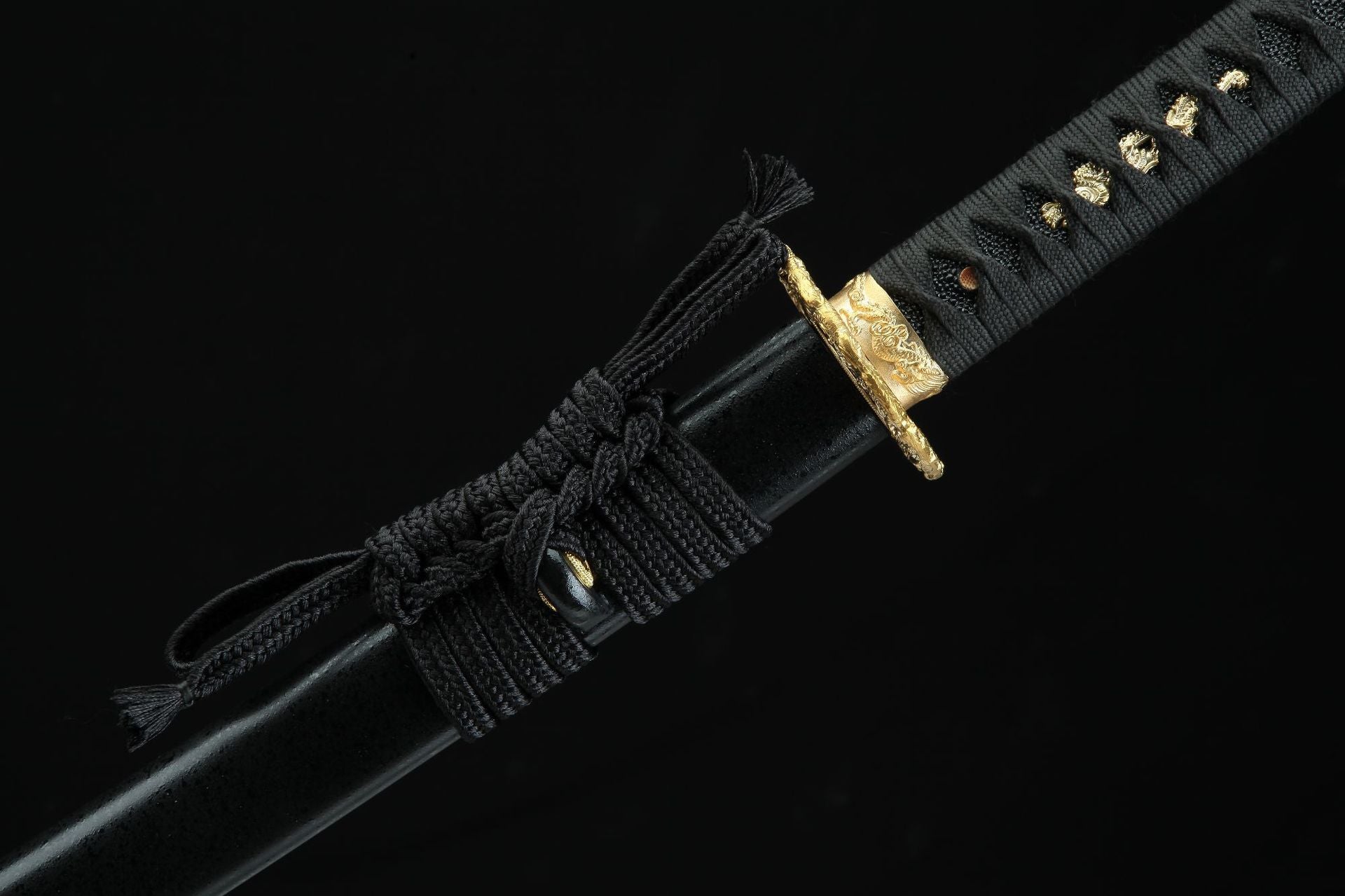 Close-up of the Golden Loong samurai sword's handle with black wrapping and sheath tied with a decorative cord.