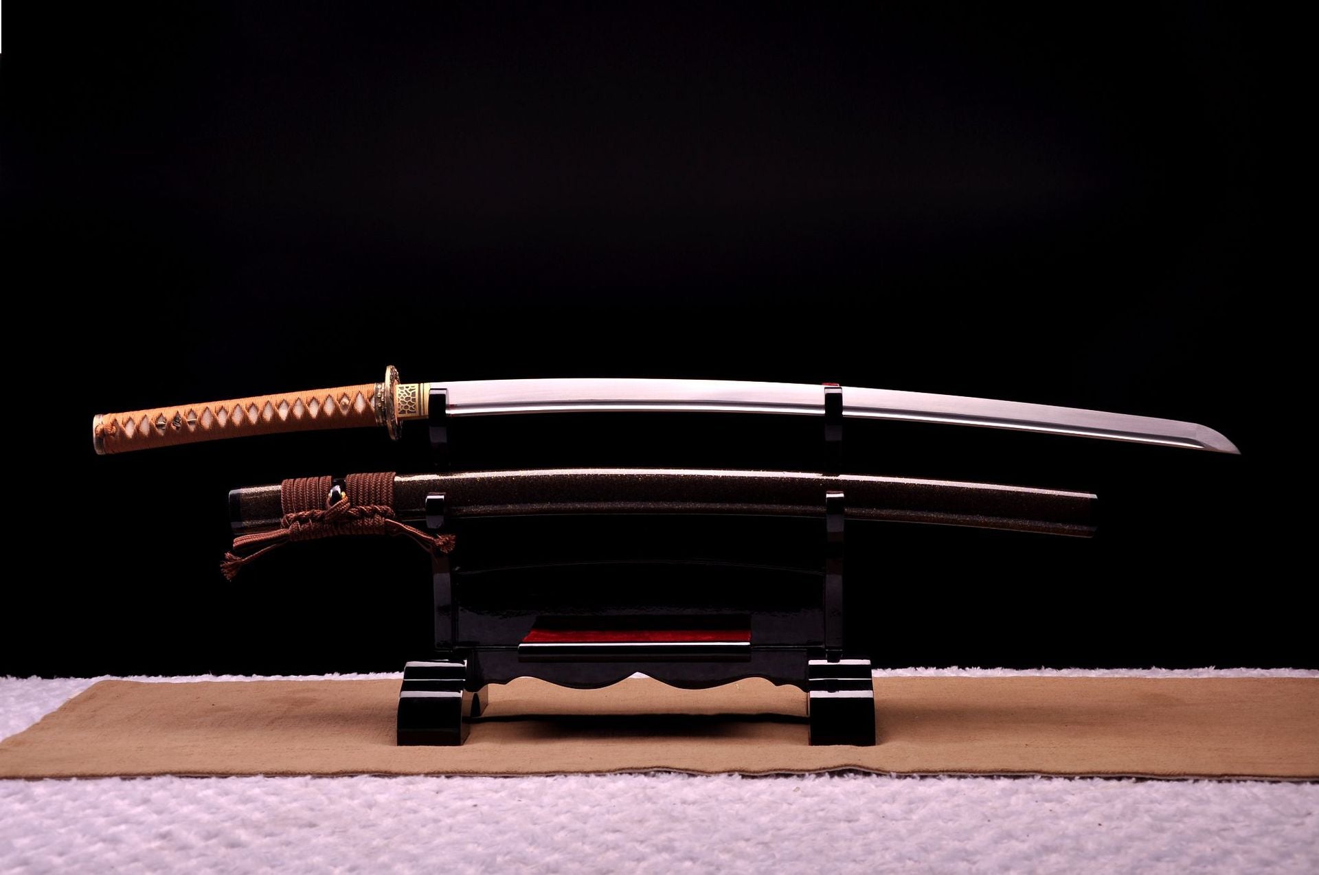 A Japanese samurai sword on a black stand with a polished blade and ornate handle.